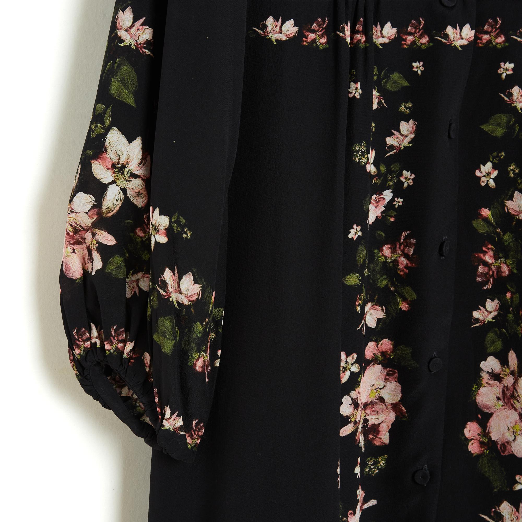 Vestido Erdem, de gran volumen y largo hasta los tobillos, pequeño cuello con muescas cerrado por 11 botones vestidos en toda la altura del vestido, cintura ceñida, 2 bolsillos con aberturas a los lados, mangas largas ligeramente abullonadas y
