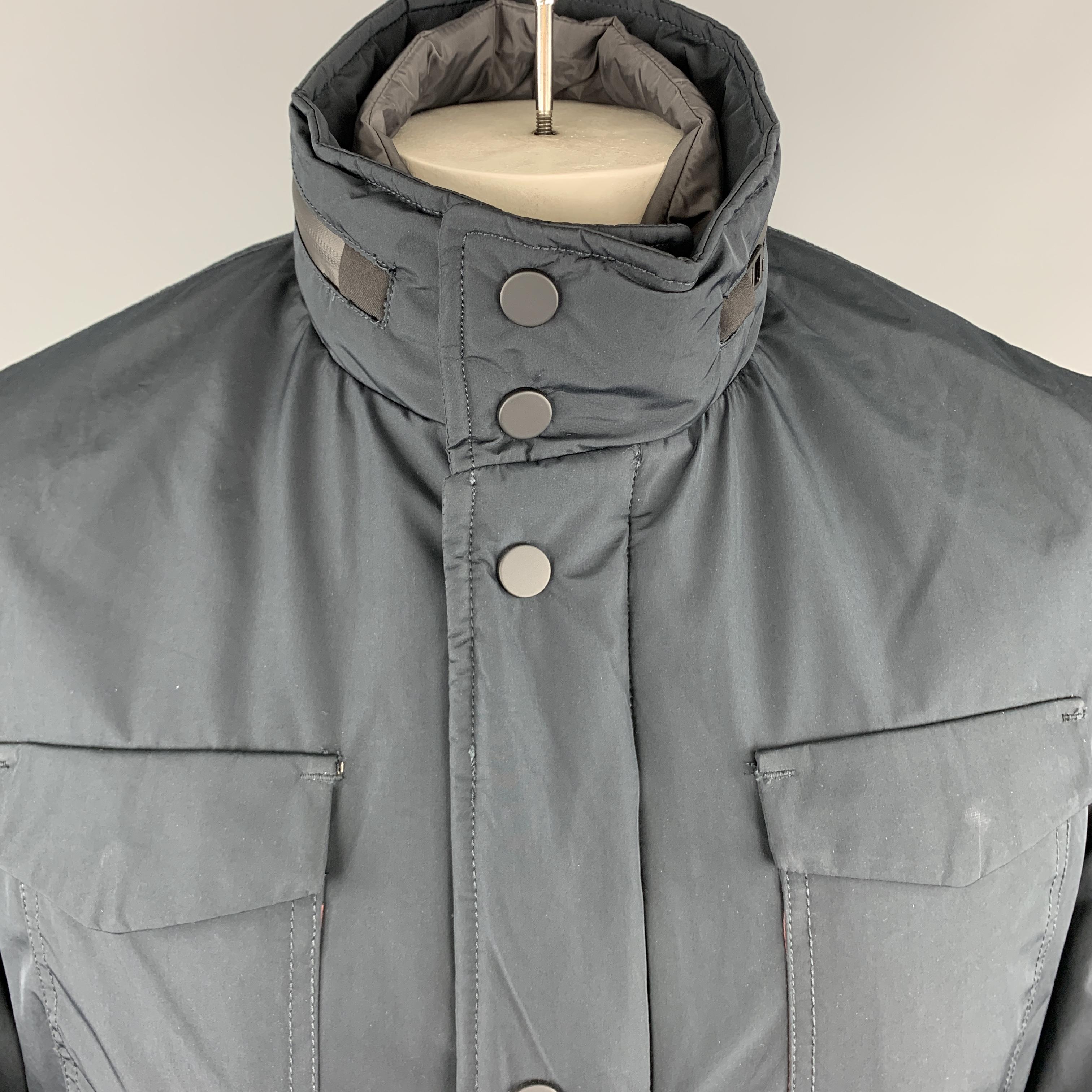EREDI PISANO jacket comes in a navy waterproof fabric with a zip up snap placket closure, patch flap pockets, waterproof zippers, high collar with tight zip out hood, and detachable front panel. Made in Italy.

New With Tags. 
Marked: