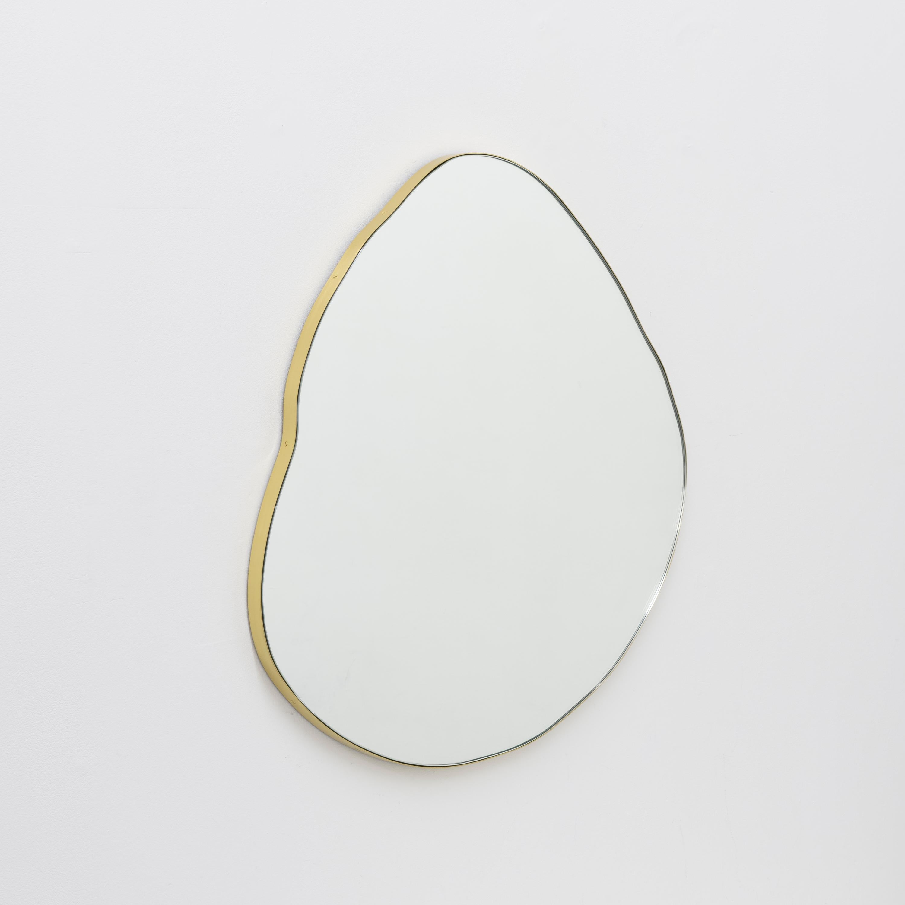 Playful and modern organic shaped mirror with a solid brass brushed frame.

Fitted with a brass hook or an aluminium z-bar (depending on the size of the mirror) that allow for the mirror to be hanged in four different positions. Also available on