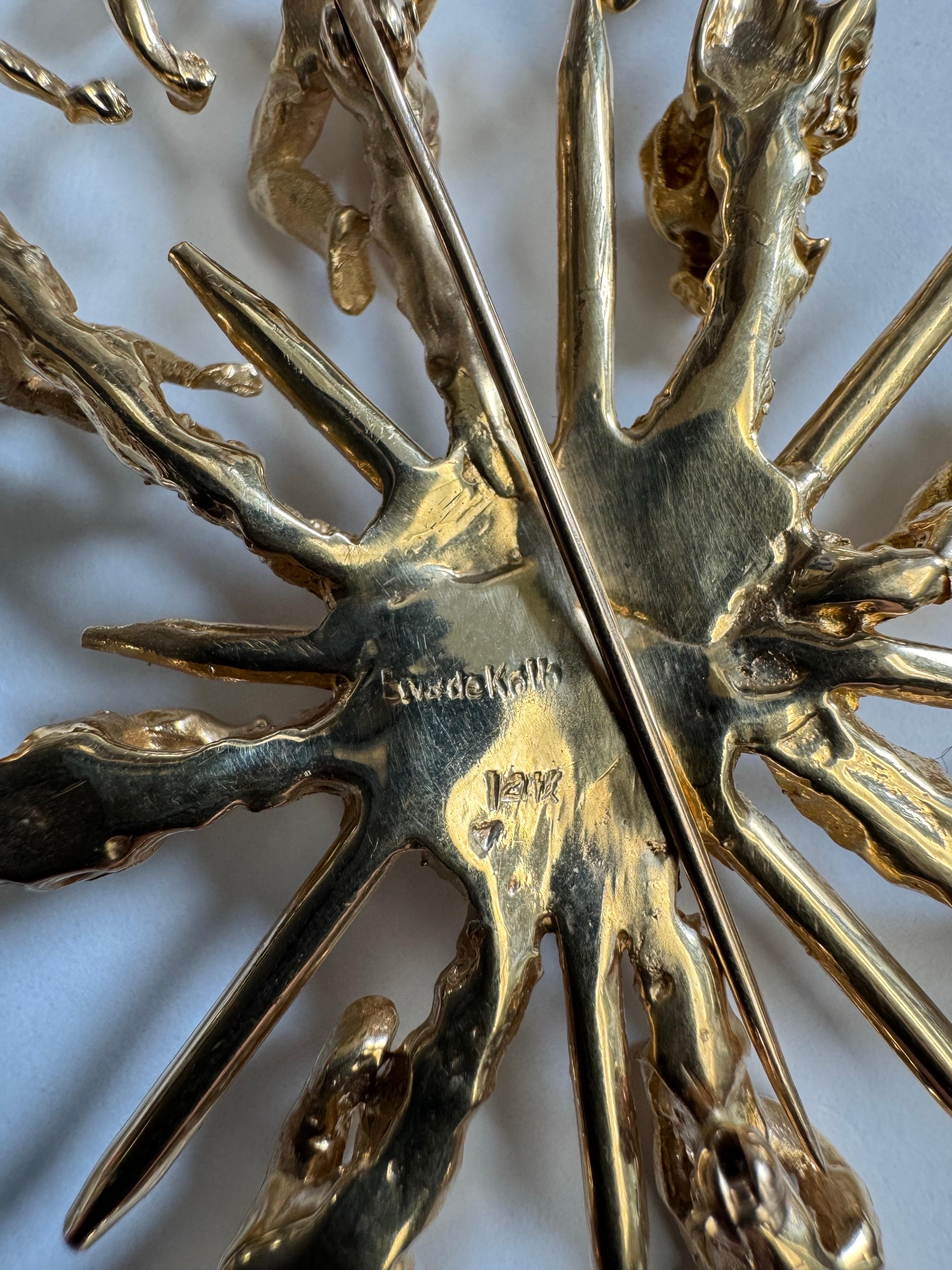 A spectacularly unique piece from the famed jewelry designer Eric de Kolb, this pin/pendant sports eight human figures - perhaps Greek or Roman gods? - arranged in a circle around a central textured motif, the figures separated by gold spikes.   The