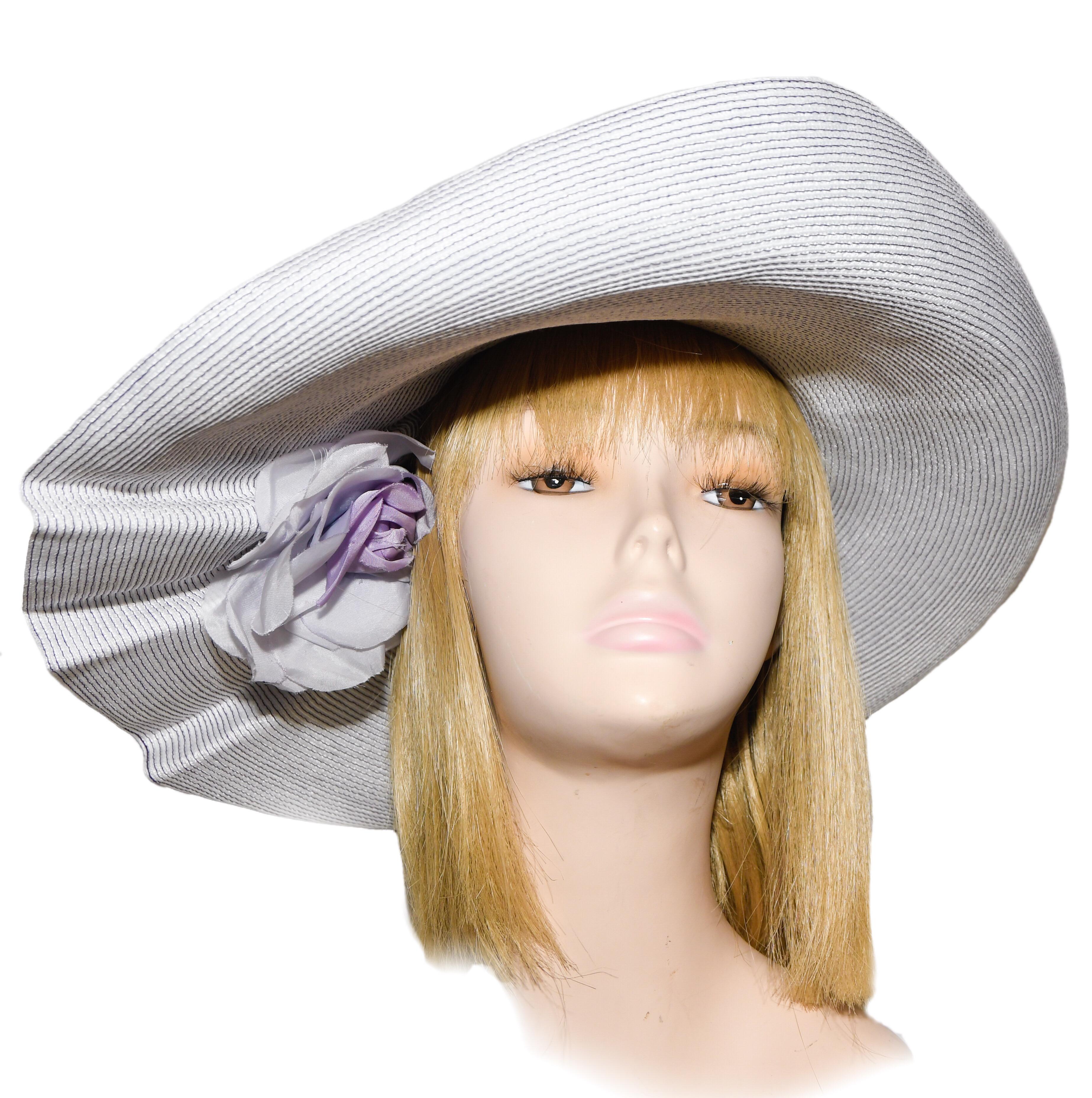 Eric Javits lavender wide brim hat with 2 lavender flowers om top of the brim  and one under the brim.  The brim, also, contains 3 pleats to accentuate the flowers. Underneath the brim another flower adorns the hairline.  This hat in excellent