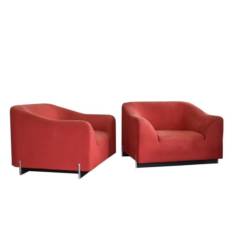 Pair of two Ligne Roset armchairs in red. This beautiful pair of modern armchairs are a wonderful way to add a bright pop of color and contrast to any room. With their fluid lines and sweeping curves, this versatile chair has become a rare ( and