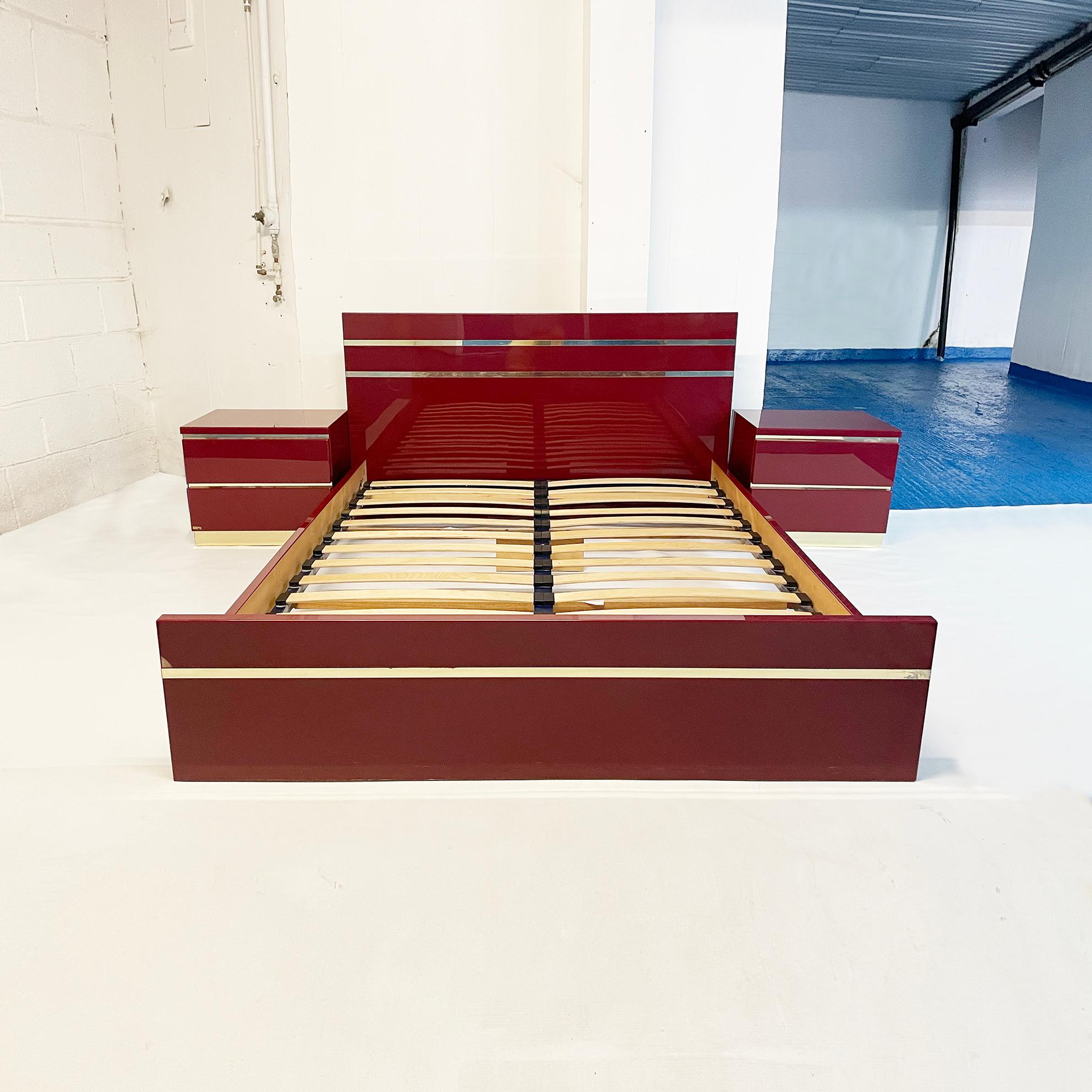 An exquisite bedroom set by the French 1970s designer Eric Maville in deep burgundy and brass. This signed French import consists of a pair of bedside tables, and a double bed in burgundy acrylic with brass trim. The bed comes with wooden double