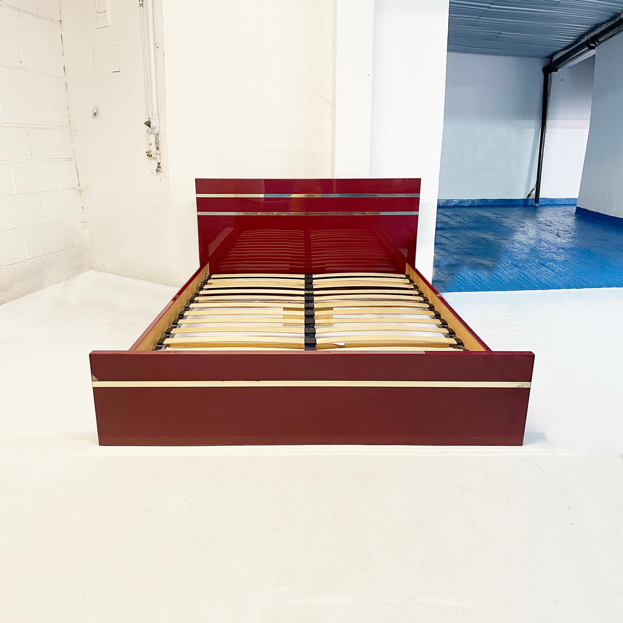 An exquisite bed by the French 1970s designer Eric Maville in deep burgundy and brass. This signed French import consists of a double bed in burgundy acrylic with brass trim. The bed comes with wooden double slats in a metal sliding frame, and it