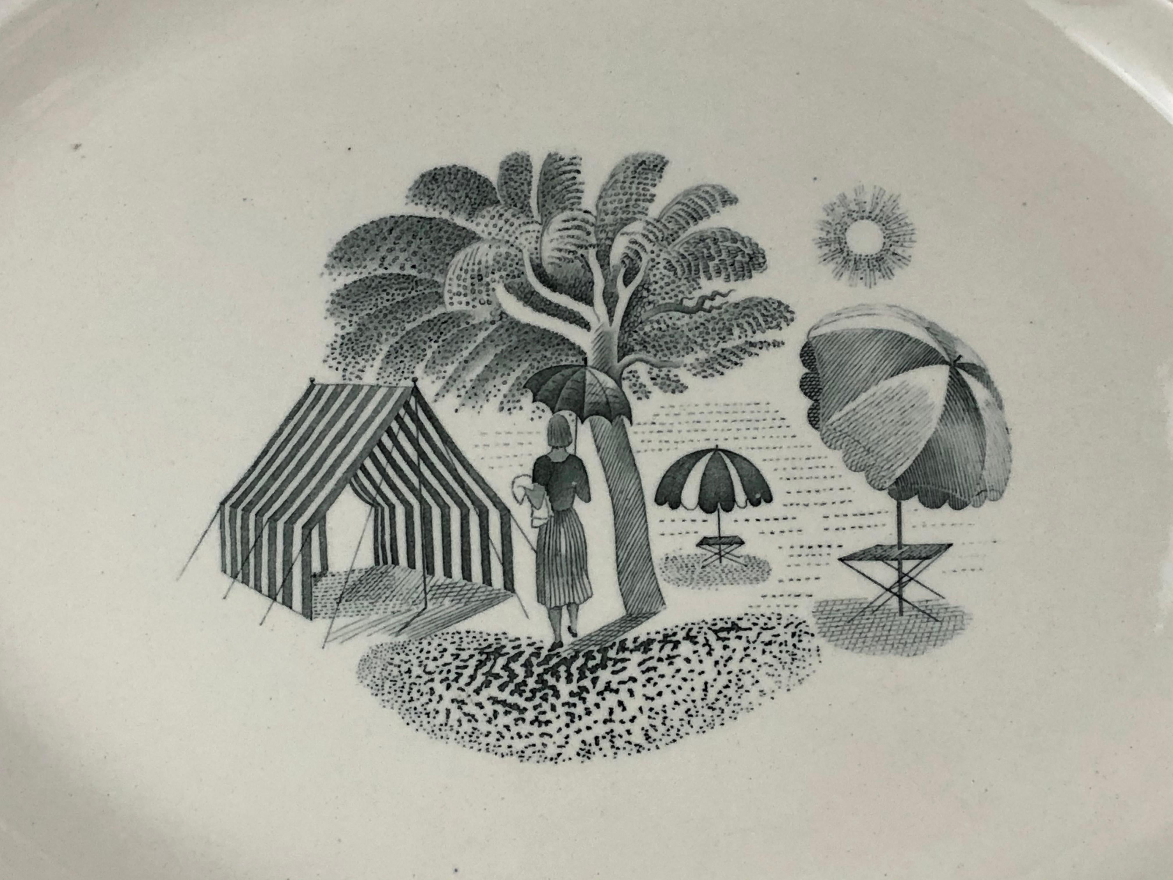 A rare, early Eric Ravilious designed oval platter for Wedgwood from the Garden Series, depicting a woman under a tree with umbrellas and a striped tent nearby, within a sunny landscape, with decorative ribbon bands around the perimeter. In transfer