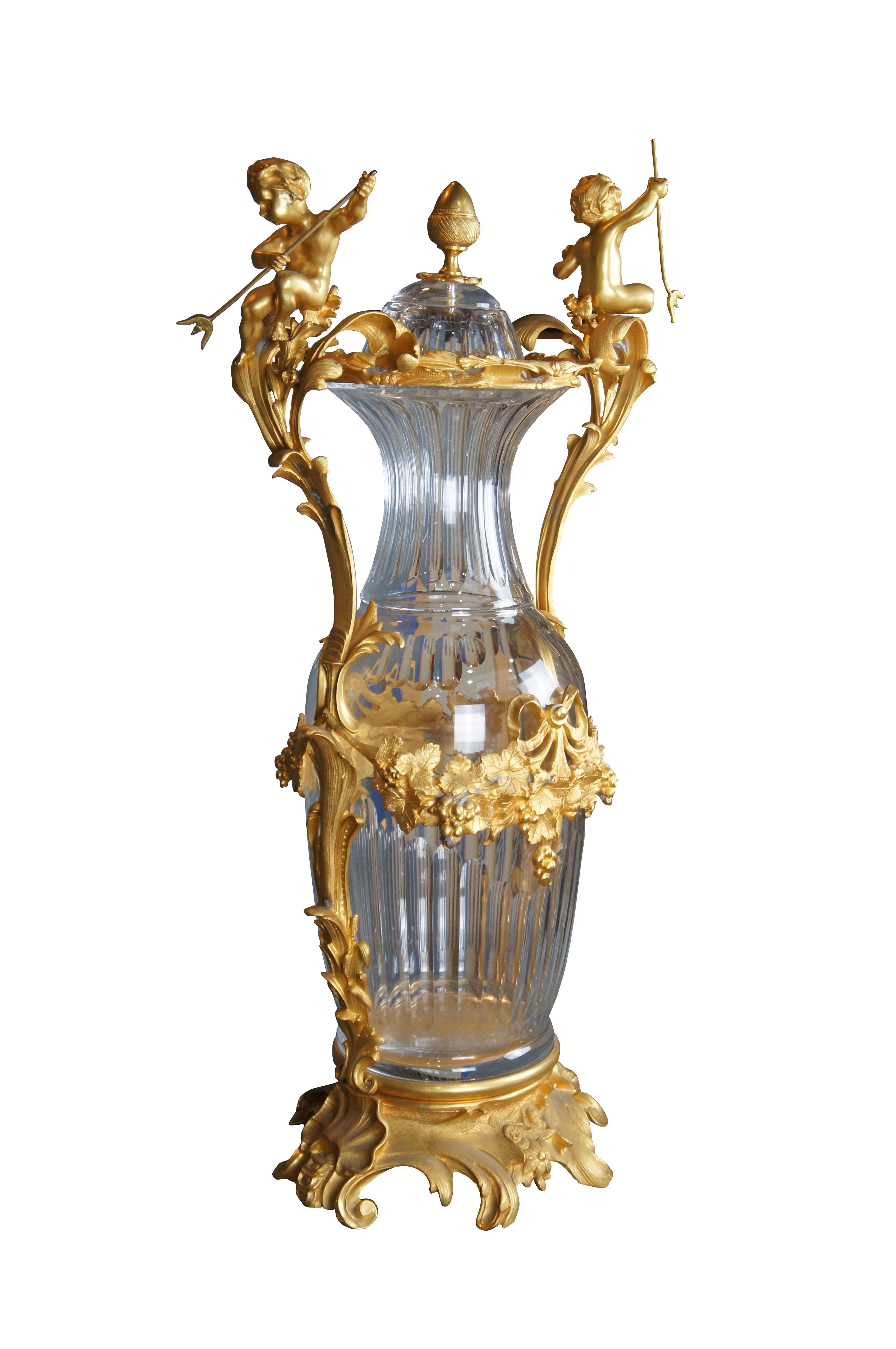 Fin du 20e siècle Eric Stepnewski Centre de table / Vase. Fabriqué en laiton ciselé ou en bronze doré, avec une finition en or 24k et en cristal. Le corps en cristal taillé cannelé est décoré de deux chérubins tenant un trident et de guirlandes de