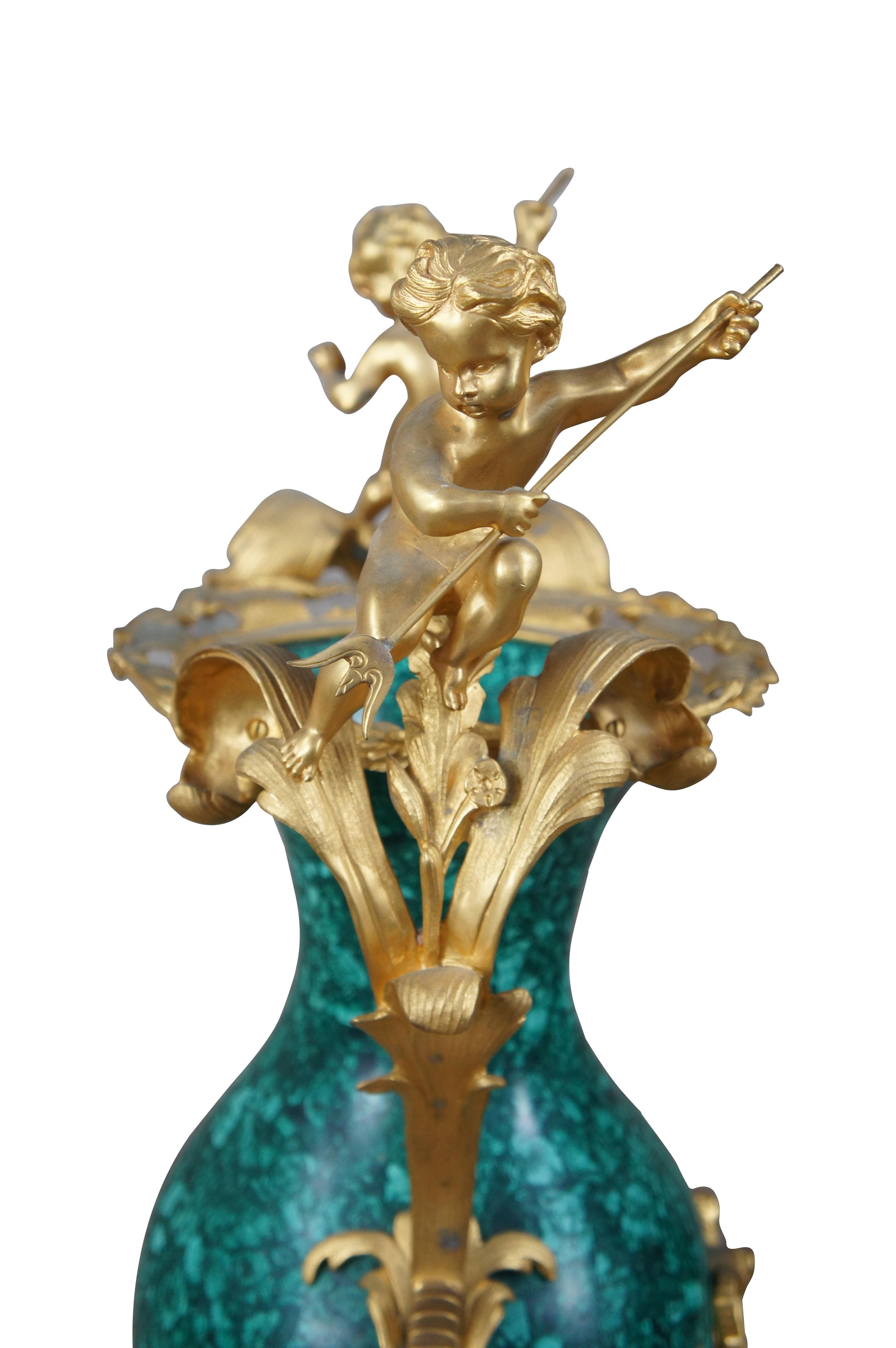 Vaso in stile rococò realizzato in ottone placcato in oro 24 carati abbinato alla pietra malachite. Decorato da due putti che reggono un tridente e da ghirlande di vite con uva. Creato da Eric Stepniewski

Dimensioni:
19,5