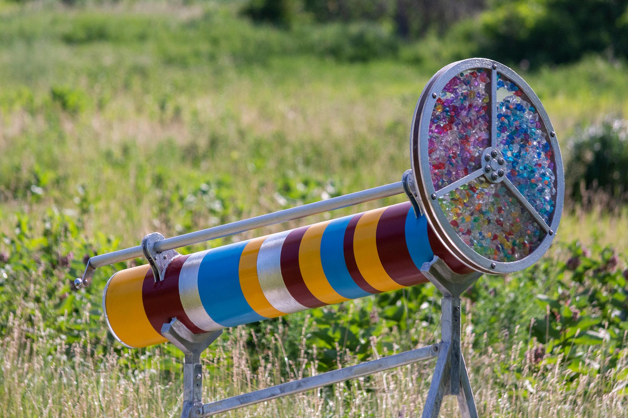 Éric Tardiff crea esculturas de exterior provocadoras y dinámicas. La obra abstracta del artista quebequés está diseñada para implicar activamente al espectador. Esta pieza de técnica mixta tiene forma de caleidoscopio y se asienta sobre un soporte