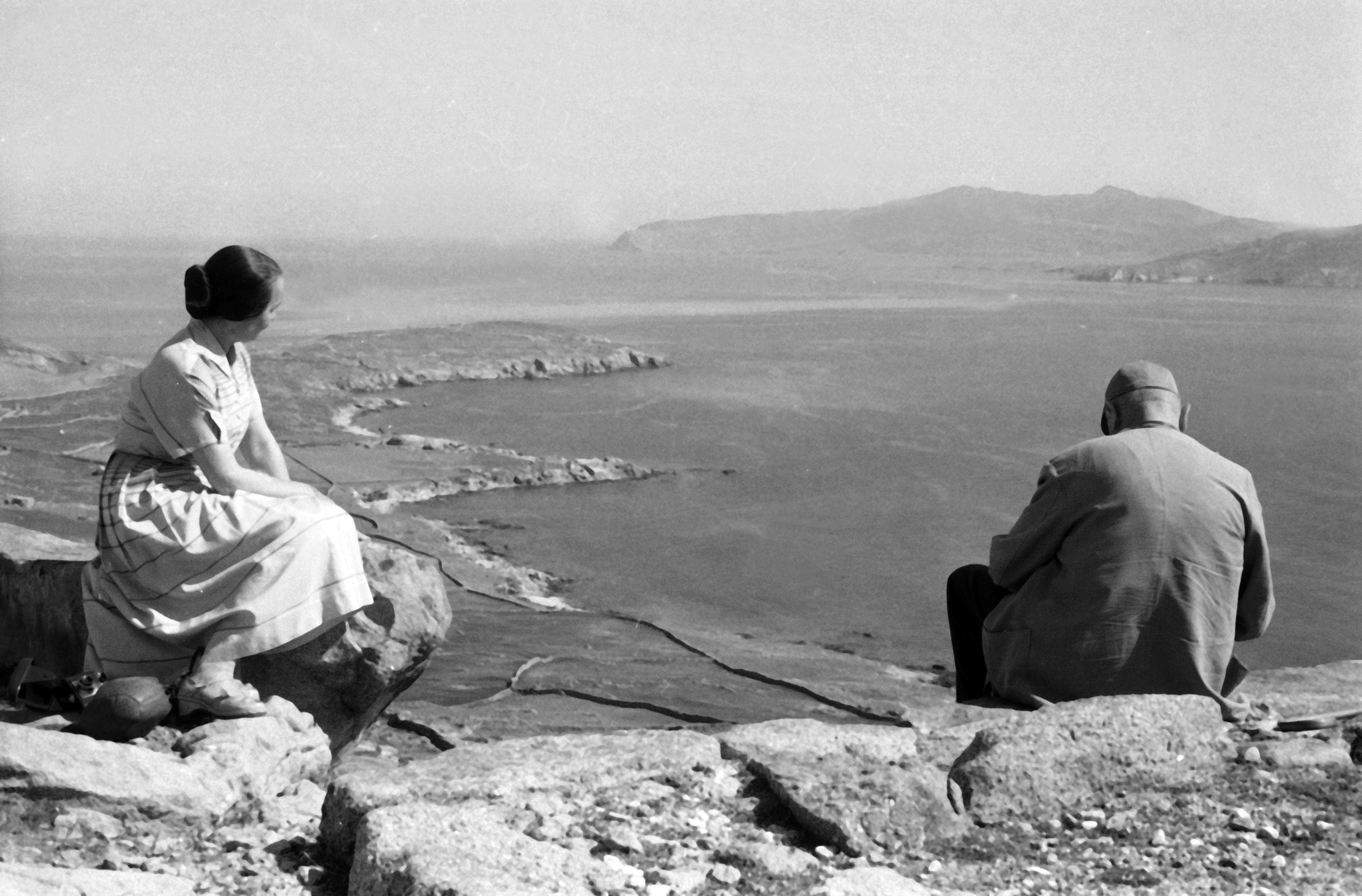 Erich Andres Landscape Photograph - Man and woman sitting on a cliff at the island of Delos, Greece 1950s
