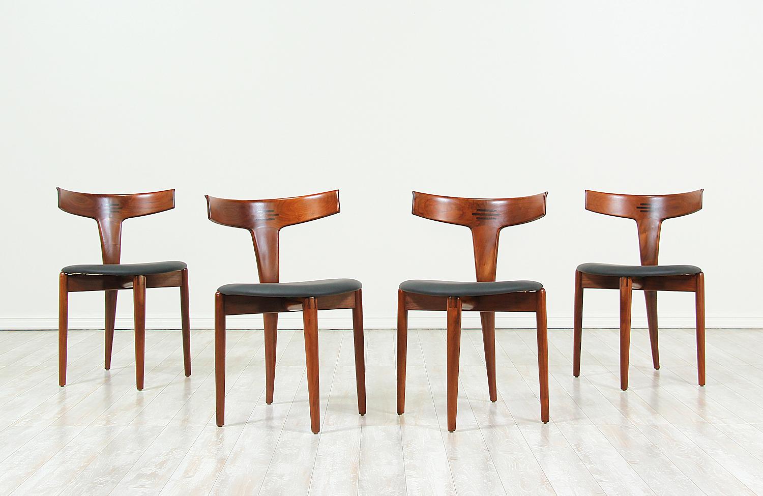 Set of four modern Danish dining chairs designed by Erik Andersen and Palle Pedersen for Randers Møbelfabrik in Denmark in 1963. This spectacular set features a solid walnut wood frame with tapered legs set in a diamond-shape and a curved backrest,