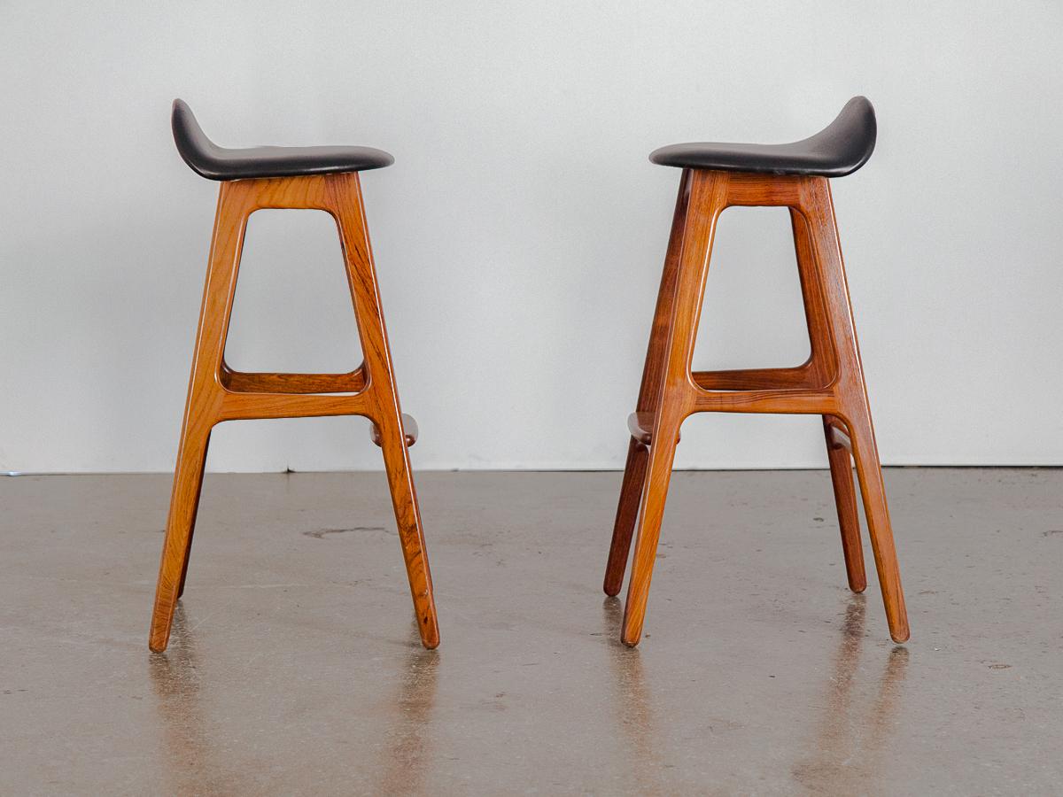 An early set of iconic barstools designed by Erik Buch, produced by Oddense Maskinsnedkeri. Low-back, padded seat covered in flawless black leather, on sinuously sculpted solid rosewood frame. Each barstool is a sturdy perch in wonderful condition.