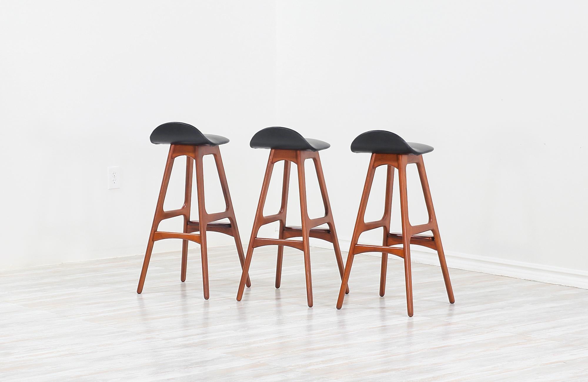 Set of three modern bar stools model 61 designed by Erik Buch for Oddense Maskinsnedkeri and manufactured in Denmark, circa 1950s. These exceptionally crafted stools feature a minimalist streamline with a solid teak wood frame and a gorgeously