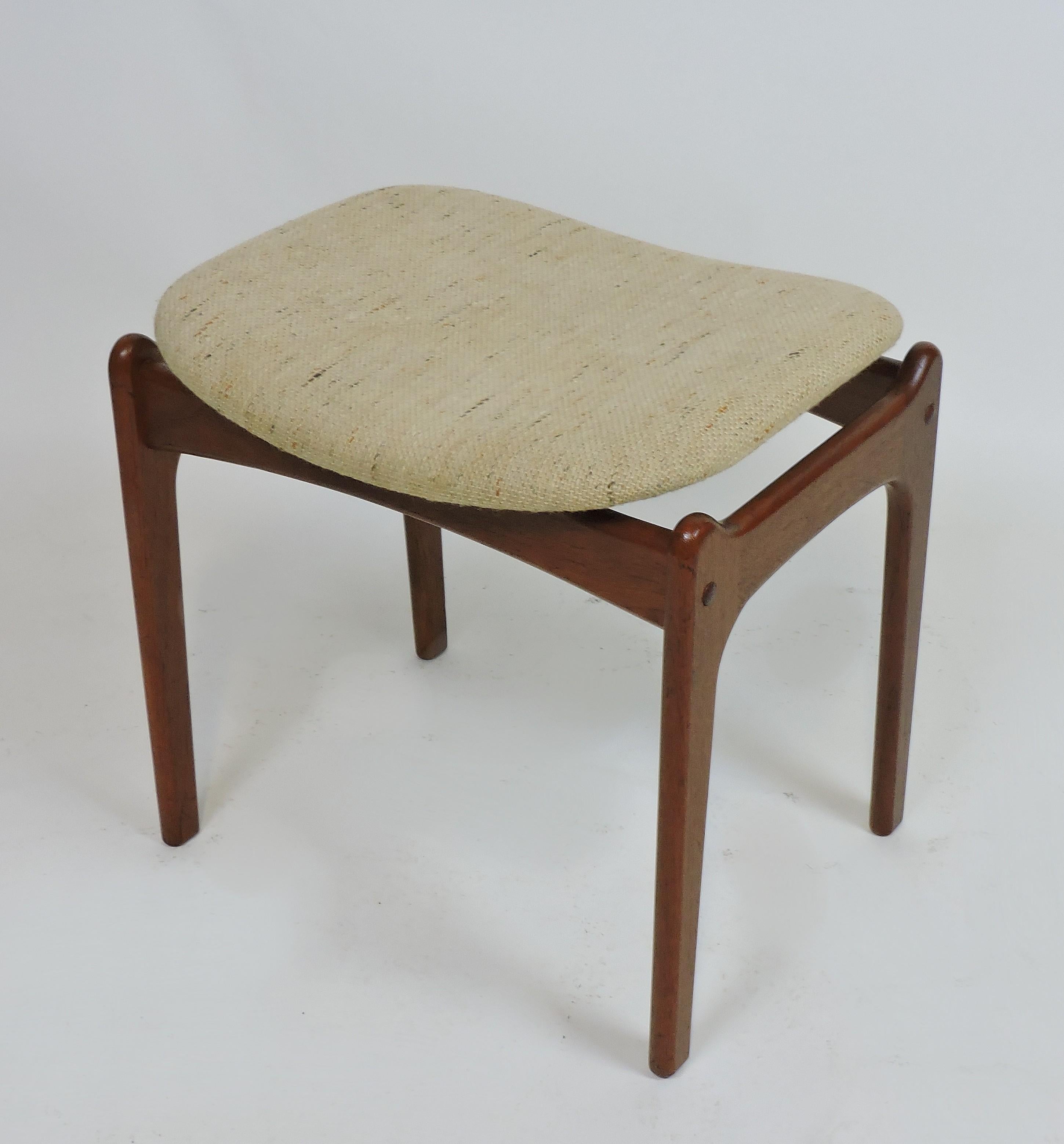 Sleek Danish modern footstool designed by Erik Buck and made in Denmark by OD Møbler. This stool is made of solid sculpted teak and has a curved seat covered in the original fabric.
