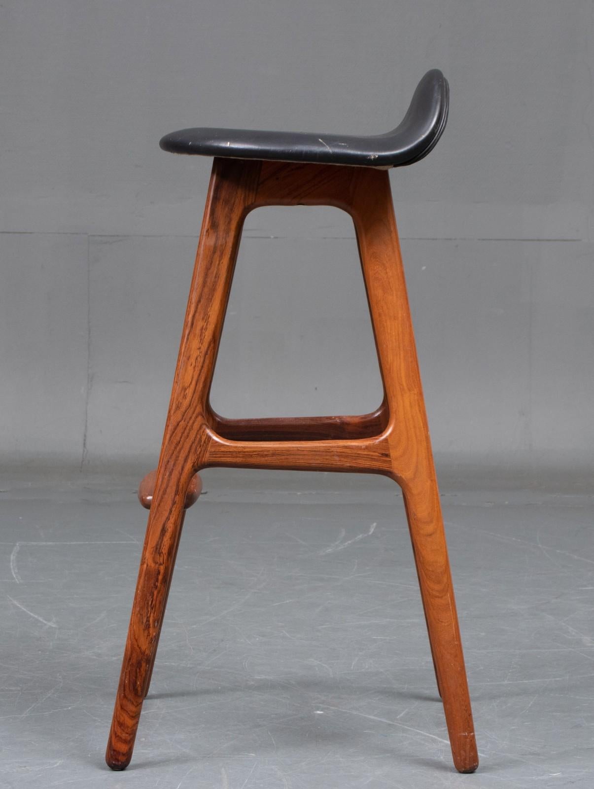 Erik Buck. Bar stool with solid hardwood frame with footrest, seat upholstered in black leather. Designed in 1965. Seat height 77cm. Manufactured by Oddense Maskinsnedkeri A / S, model OD 61. Appears with normal. age-related traces of use. 
Only
