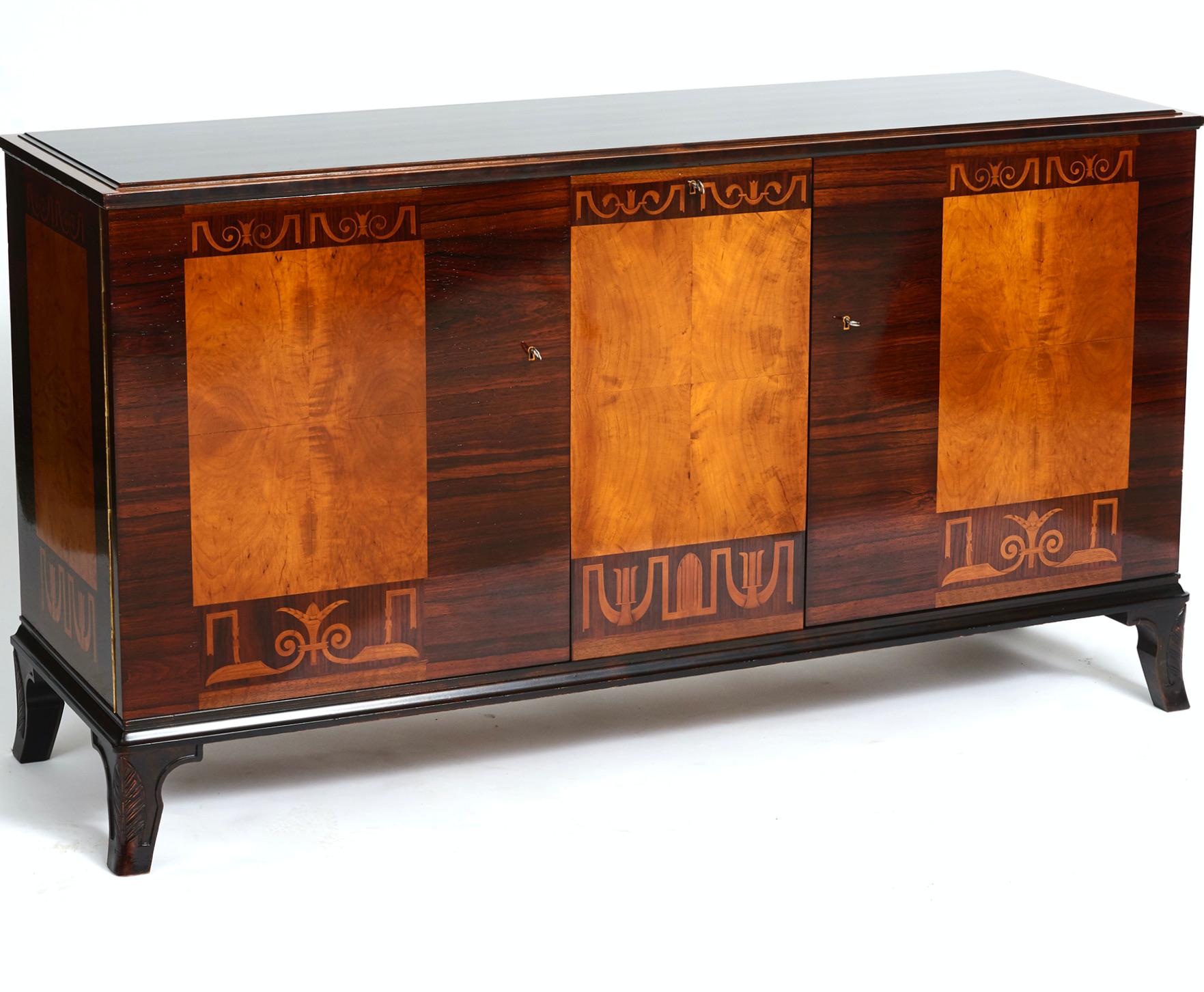 A Swedish inlaid and stained birch sideboard, designed by Erik Chambert, circa 1940s, the rectangular top with a molded edge above two cupboard doors and a central tilting bottle compartments. Shelves inside. The base raised on carved out curved
