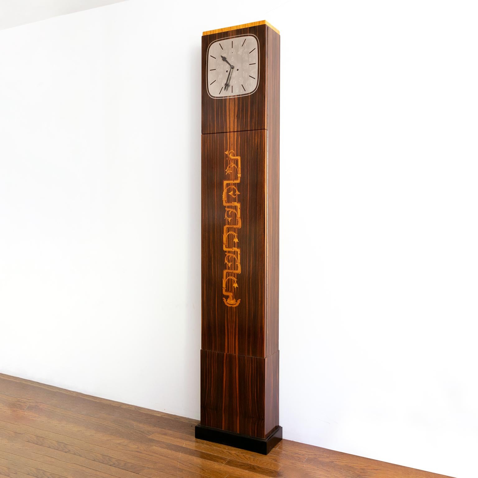 Erik Chambert, Swedish Art Deco floor clock in rosewood and decorative marquetry depicting stylized foliage. The clock’s face is polished pewter with engraved imagery all of which refer to the passing of time, zodiac figures, stars, our sun & moon,
