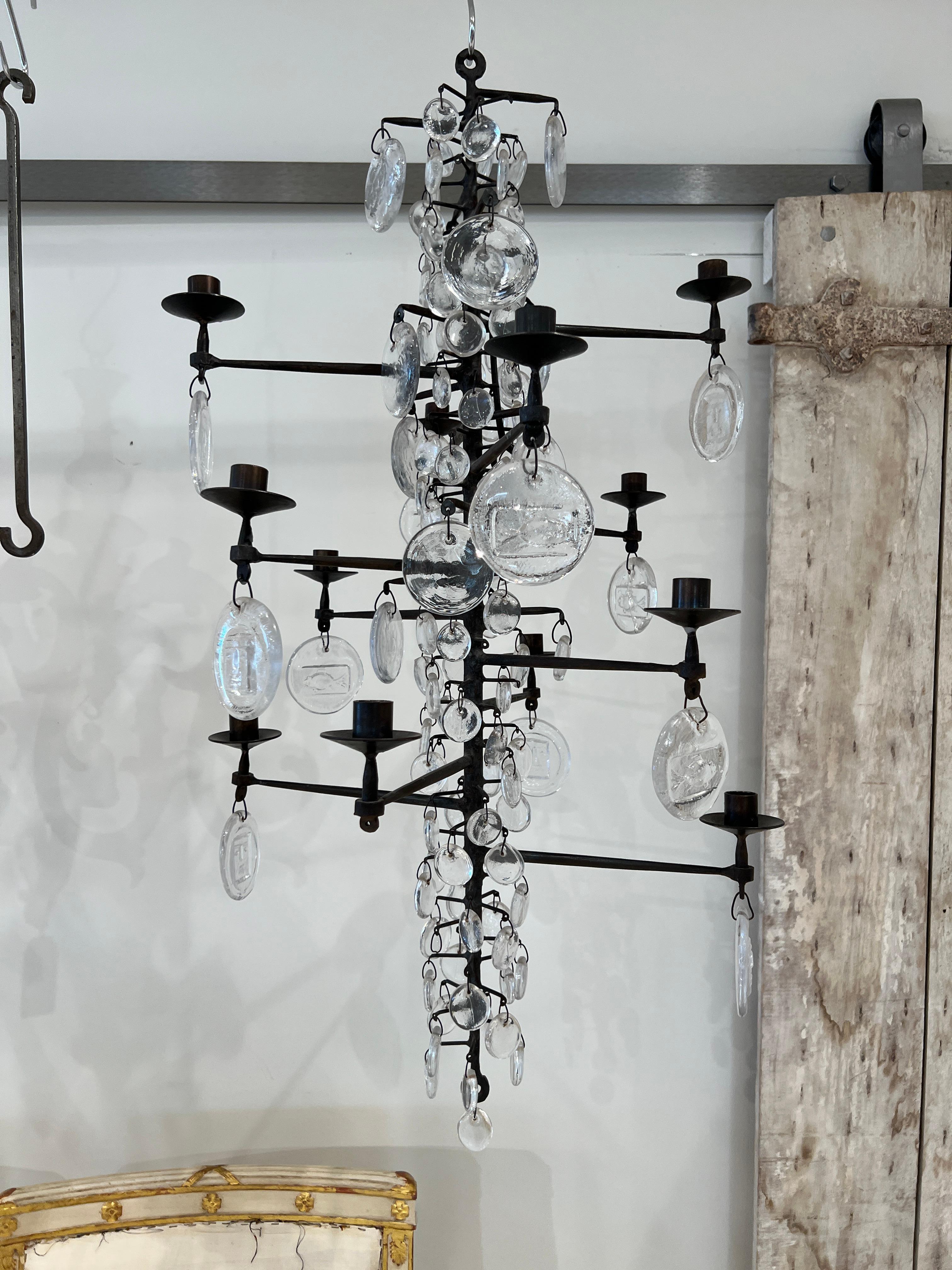 Classic midcentury chandelier by Erik Hoglund. Made of wrought iron and molded glass, this twelve-light chandelier was made by Erik Hoglund for Kosta Boca. There is one large and 4 small glass discs missing.  Not wired for electricity.