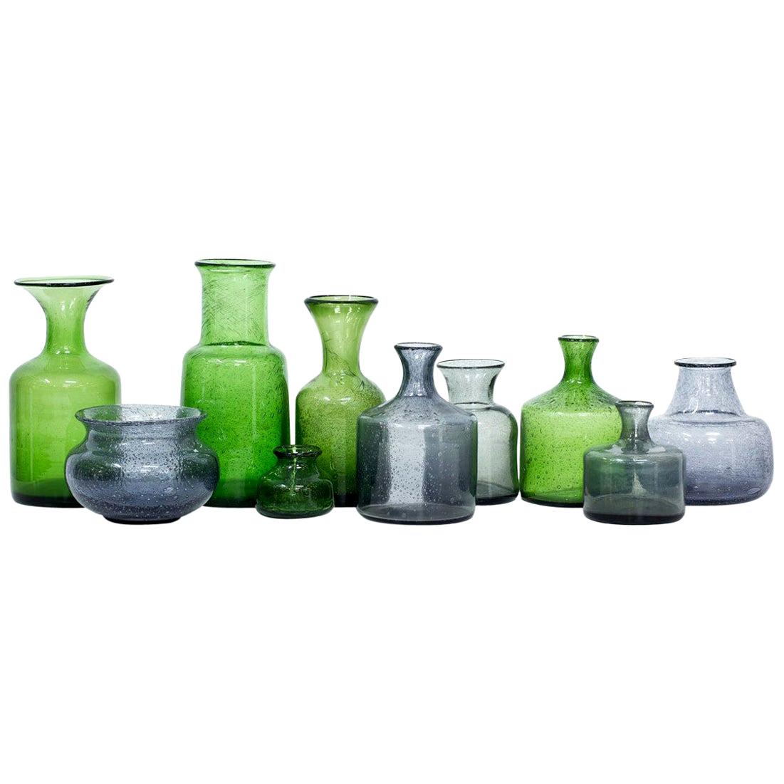 Collection of ten glass vases designed by Erik Höglund.
Mouth blown at Boda glass factory in Sweden during the 1950s.
Group of grey and green vases of various sizes and shapes, all with air bubbles in the glass.
All vases are engraved underneath.