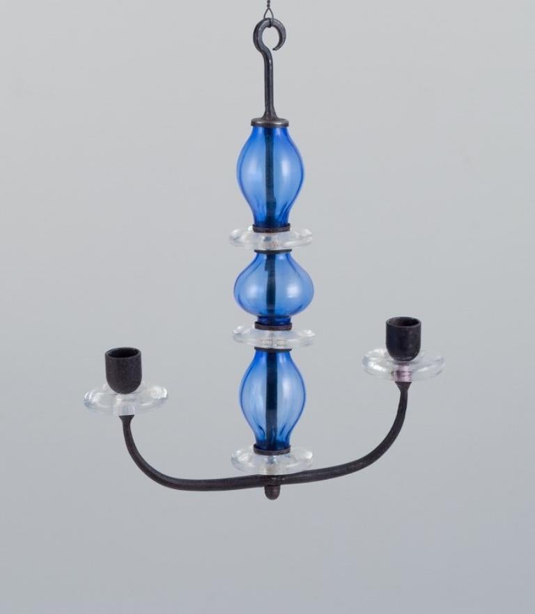 Erik Höglund (1932-1998) for Kosta Boda, Sweden. 
Rare two-armed hanging candle holder in cast iron and mouth-blown art glass.
Mid-20th century.
In perfect condition.
Dimensions: H 35.0 cm x W 27.0 cm x D 6.5 cm.
