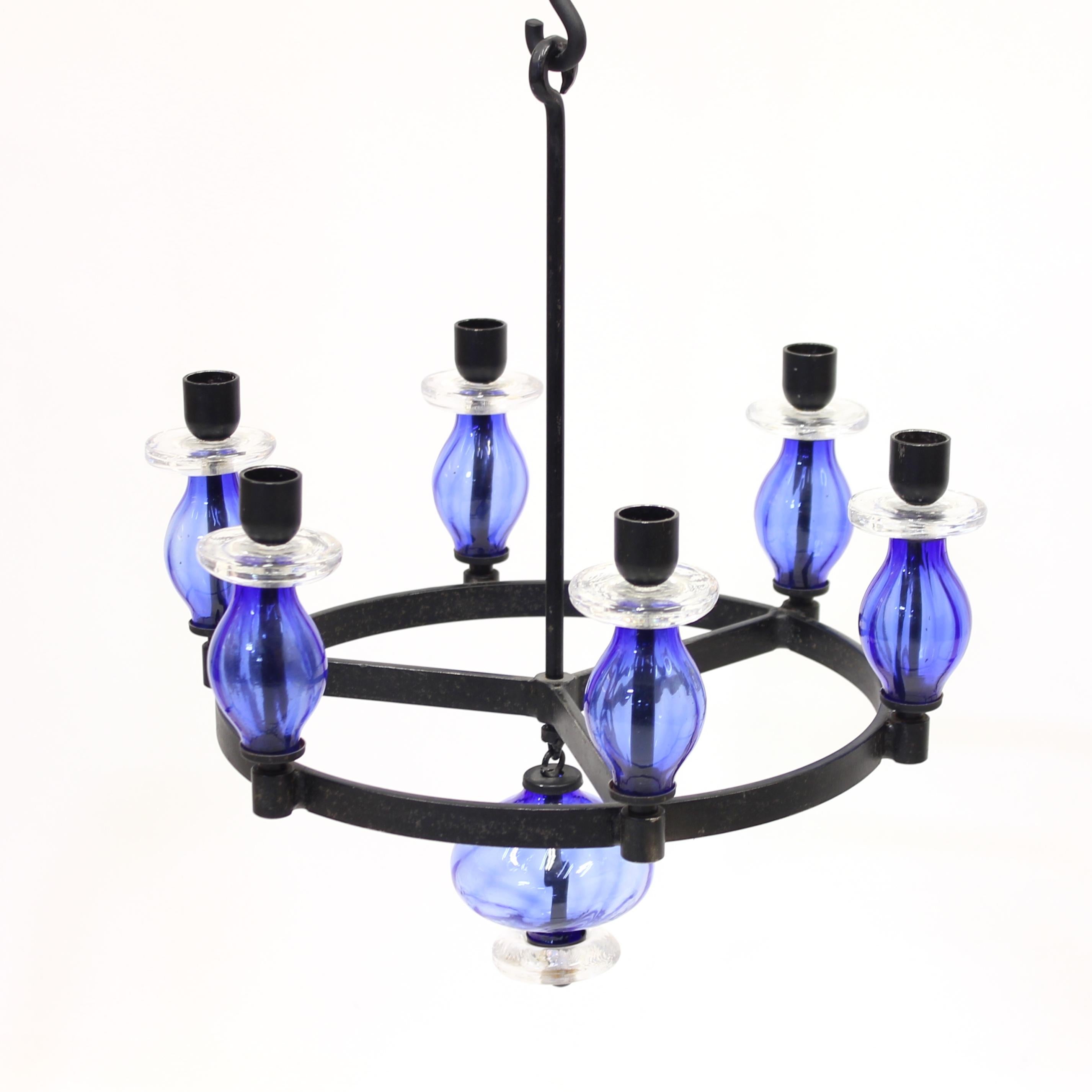 Rare Erik Höglund glass and wrought iron chandelier for 6 candles. Made by Swedish manufacturer Boda Glasbruk & Smide in the 1960s. Round black frame and hooks of wrought iron with blue and clear glass decoration. The number of hooks that the