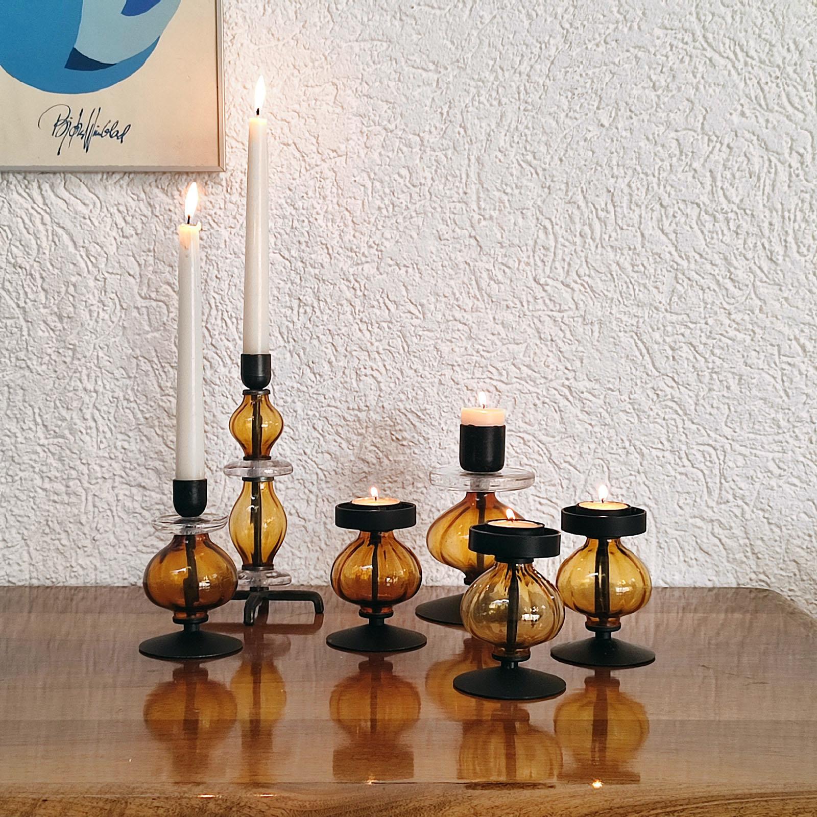 Mid-Century Modern, Swedish, set of four candle holders, black painted metal and amber art glass, designed by Erik Hoglund for Boda, Sweden. Base and top made of black painted metal. Body made of ribbed amber art glass to get an artistic visual