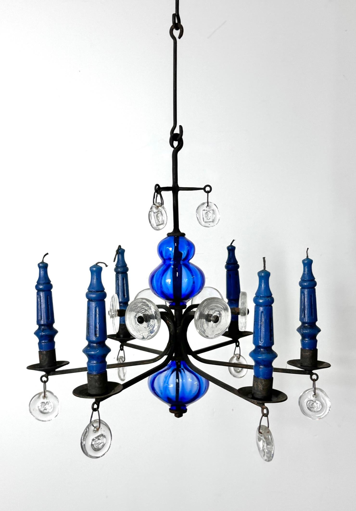 Candelabro colgante de Erik Hoglund para Boda Sweden circa 1960s

Lámpara de hierro forjado de seis brazos con centro de cristal soplado azul cobalto con adornos transparentes y medallones colgantes
Incluye dos elementos para colgar y velas