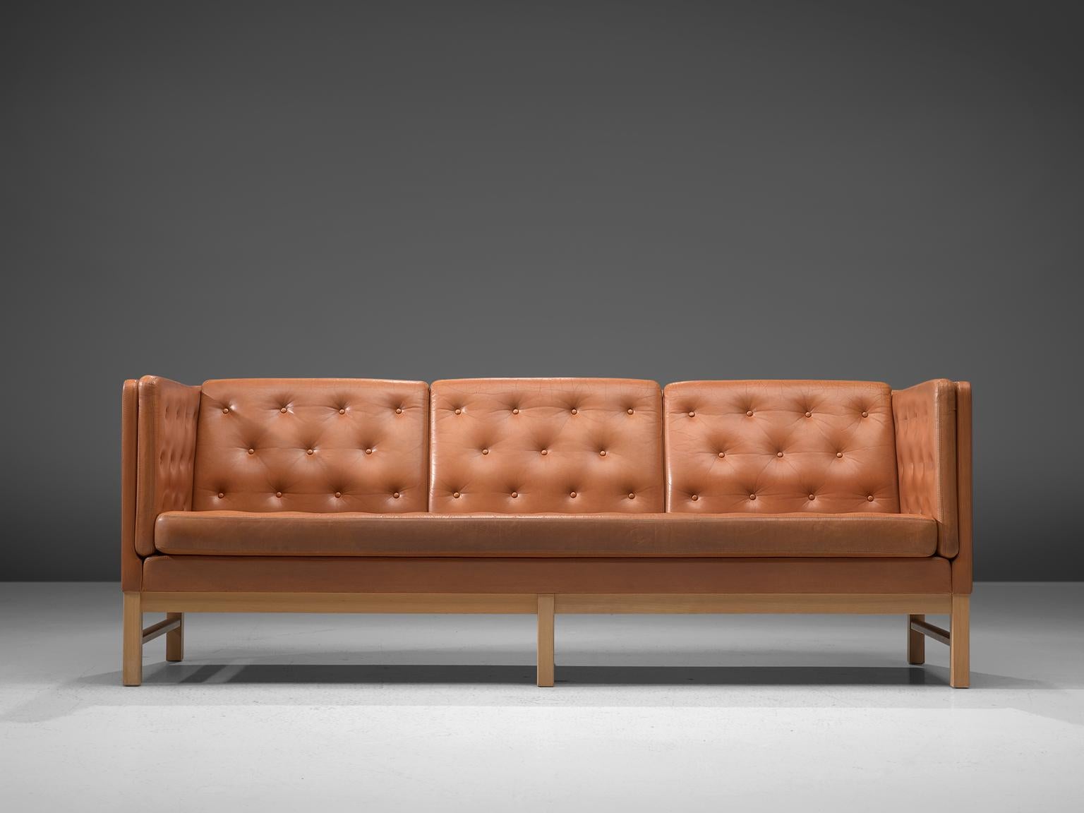 Erik Ole Jørgensen for Erik Jorgensen Møbelfabrik, sofa model EJ 315-3, wood and leather, Denmark, 1972. 

Elegant three-seat sofa by Erik Ole Jørgensen. This sofa has a luxurious appearance due to the tufted cognac leather. The orderly placed