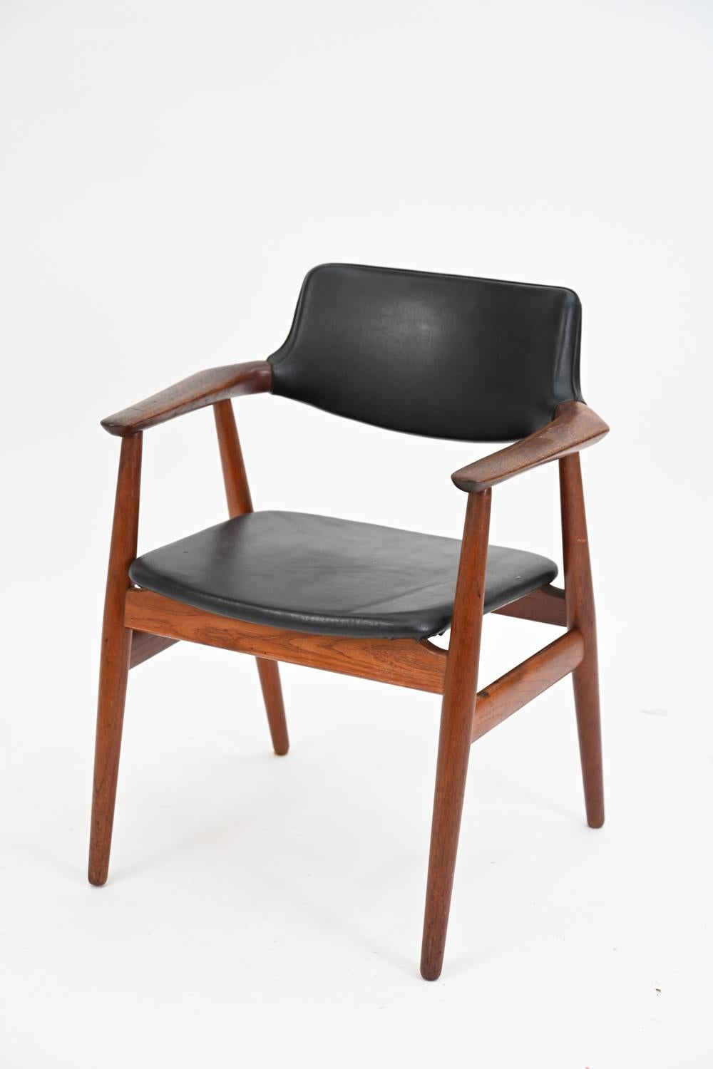 A stylish Danish mid-century armchair designed by Erik Kirkegaard, c. 1960's. This Scandinavian modern chair features a teak frame with striking angles and black vinyl upholstery. A great accent piece for a living space.