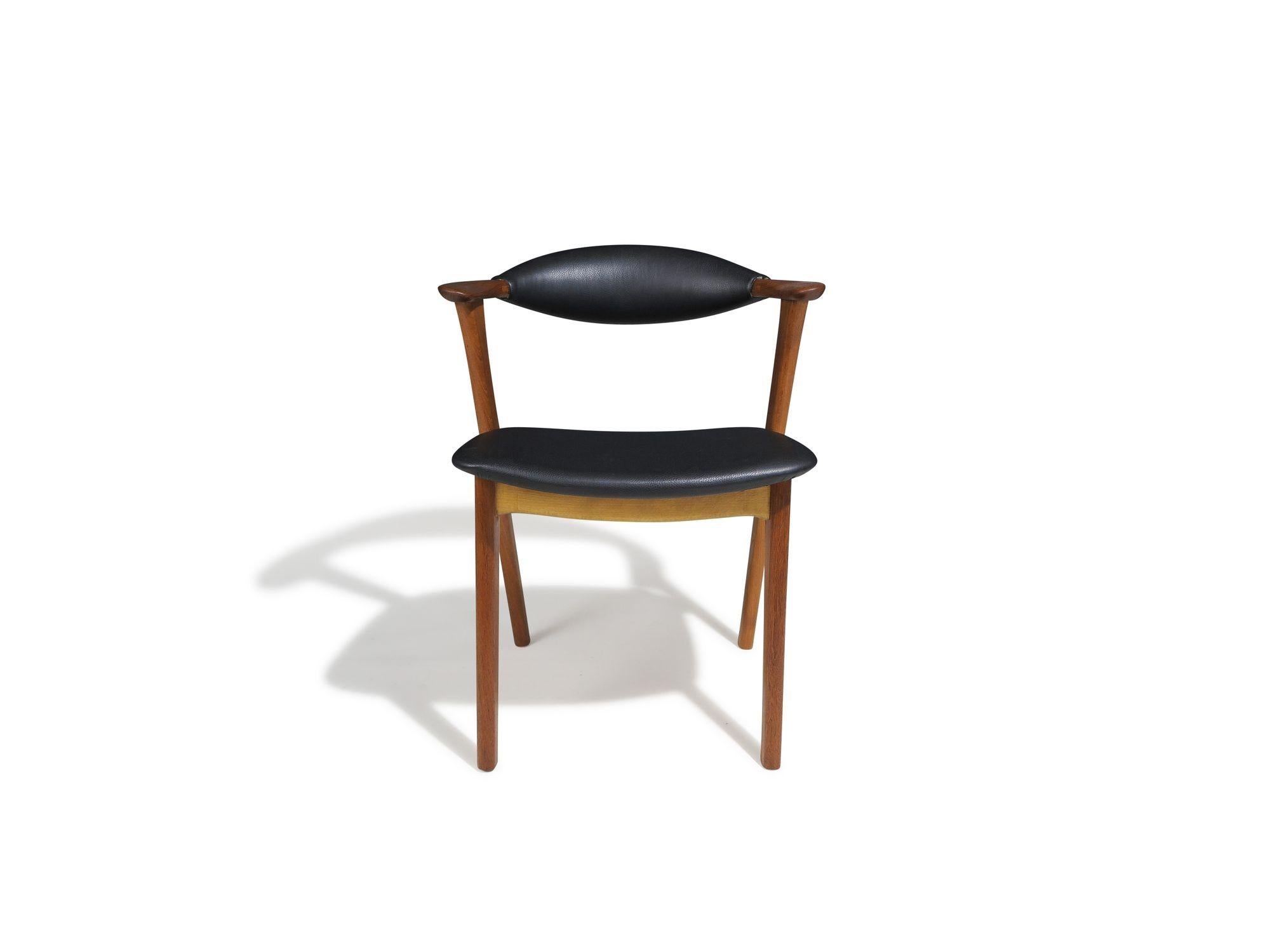 Eight dining chairs designed by Erik Kirkegaard, 1956, model 43 Denmark. Handcrafted of solid teak with sculpted teak arms and sturdy frames, upholstered in black leather. Professionally restored and in excellent condition with minor signs of age