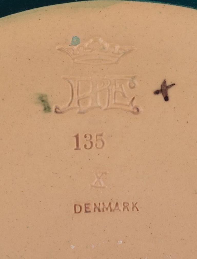 Erik Magnussen für Ipsen, Dänemark. 
Jugendstil-Schale aus handbemalter Keramik, modelliert mit Ranken und Blattwerk.
Modellnummer 135.
Aus den 1920er Jahren.
In perfektem Zustand.
Gestempelt.
Abmessungen: Durchmesser 31,0 cm x Höhe 5,5 cm.
