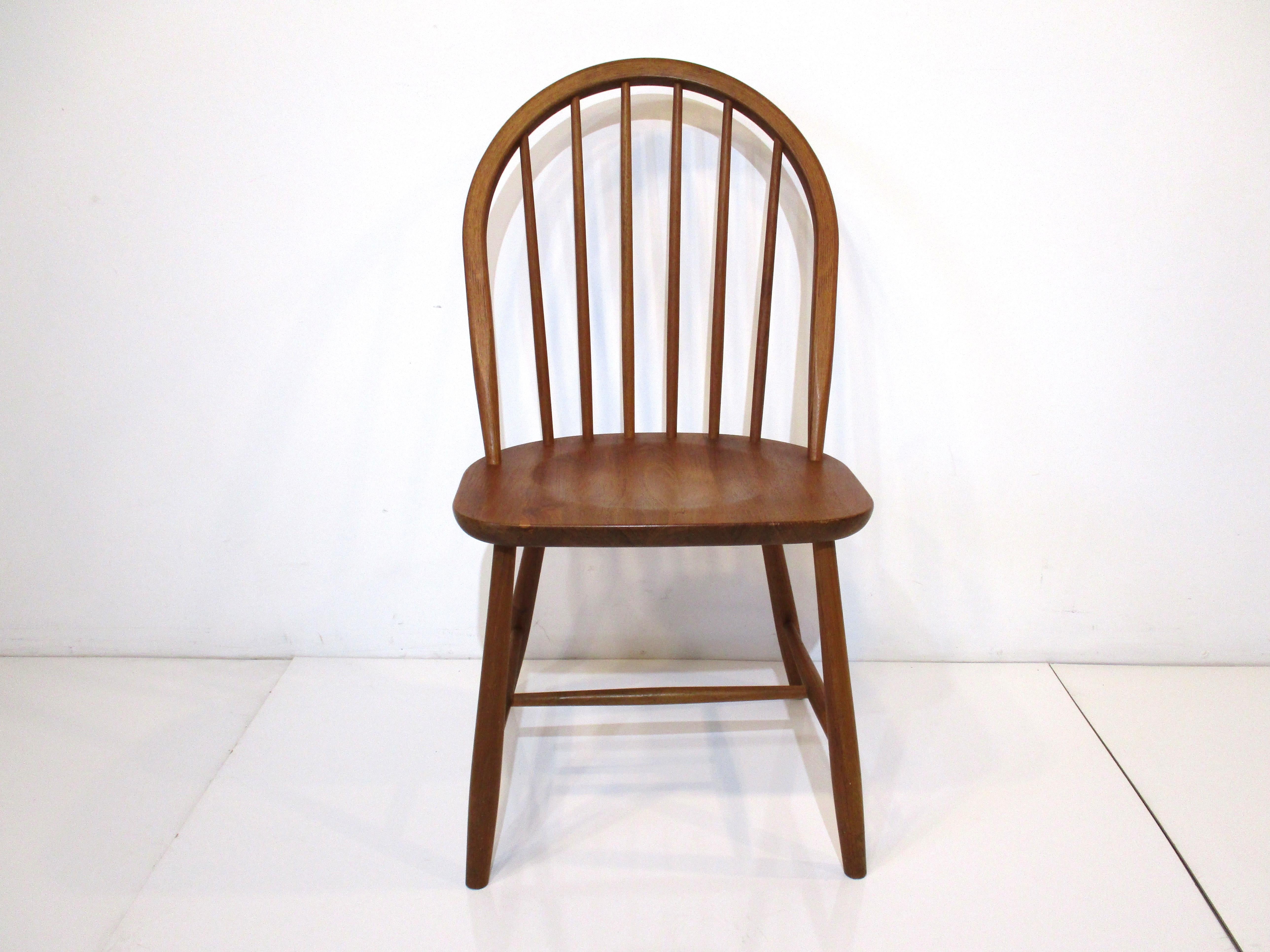 A set of six spindle back curved framed teak wood dining chairs consisting of four with U shaped seats and two head chairs with curved edged seats. Well constructed and very sturdy these would work with many different styles and interiors. Designed