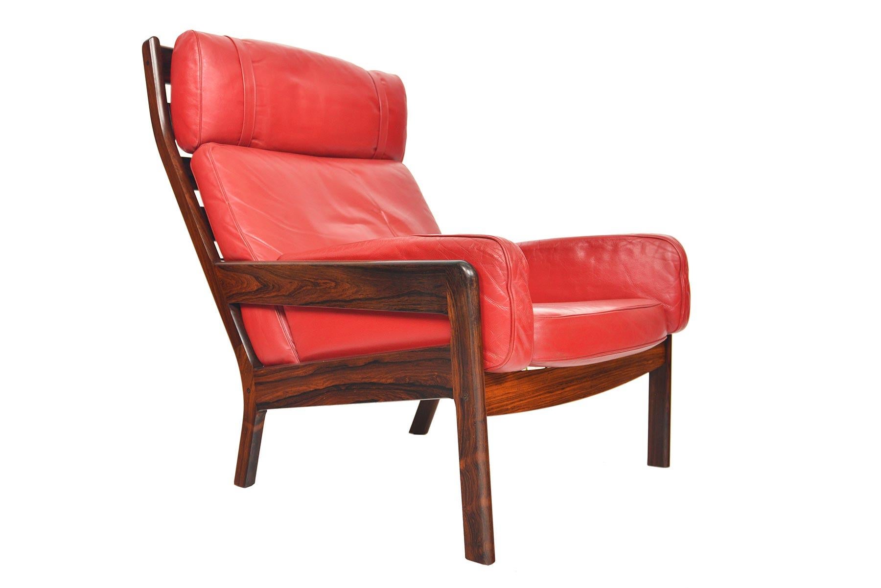 This beautiful Erik Ole Jørgensen highback lounge chair was produced for Georg Jørgensen + Son in the 1960s. This streamlined Model GJ 13 chair is covered in a vibrant red leather. Five leather cushions rest in the highback frame with original brass