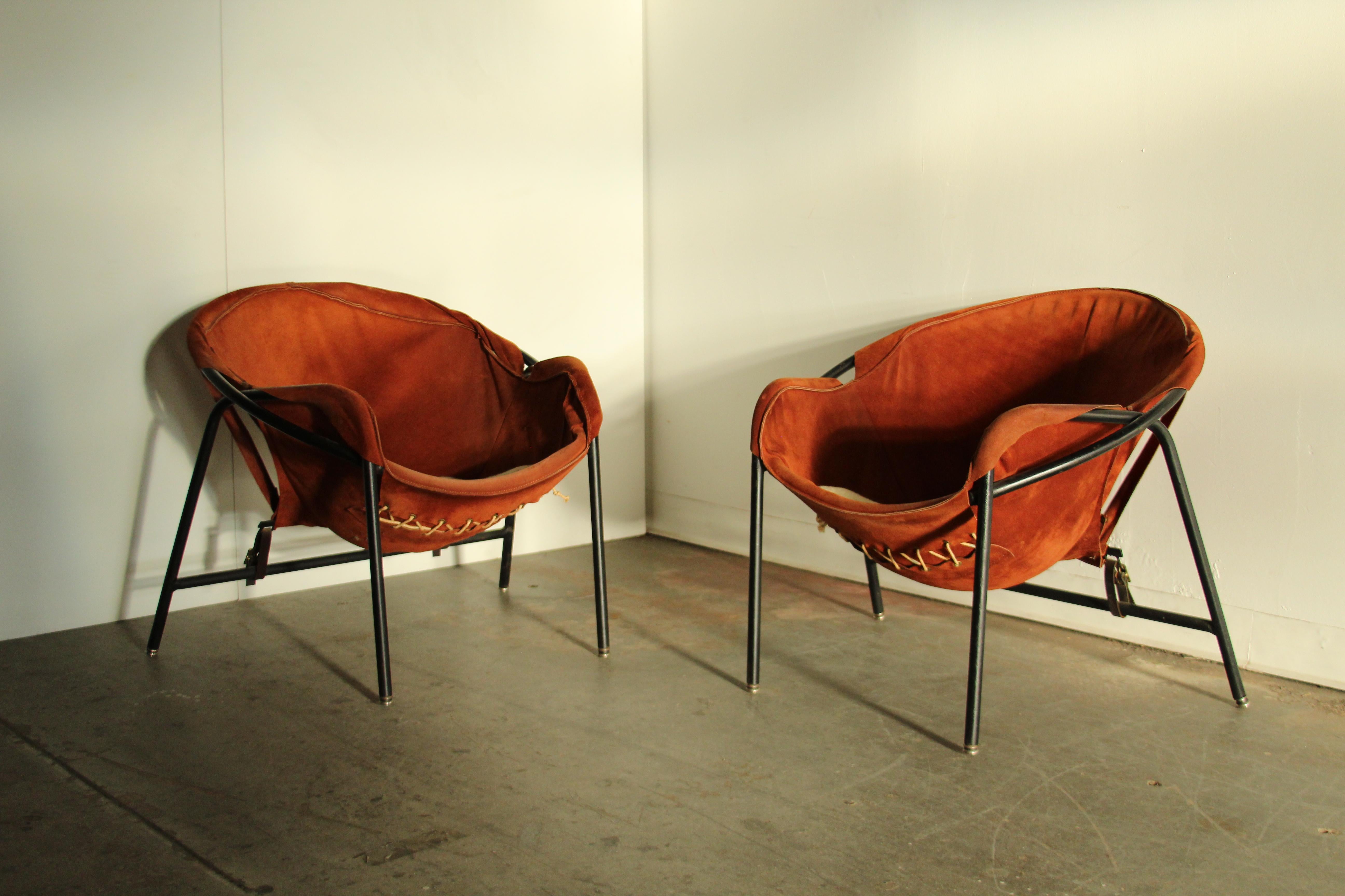 A fabulous pair of easy chairs designed by Erik Ole Jørgensen and produced by Bovirke in the 1950s. Original suede sling seats with visible rope detailing on underside. Blackened steel frame with self-leveling feet. Charming leather buckle straps on