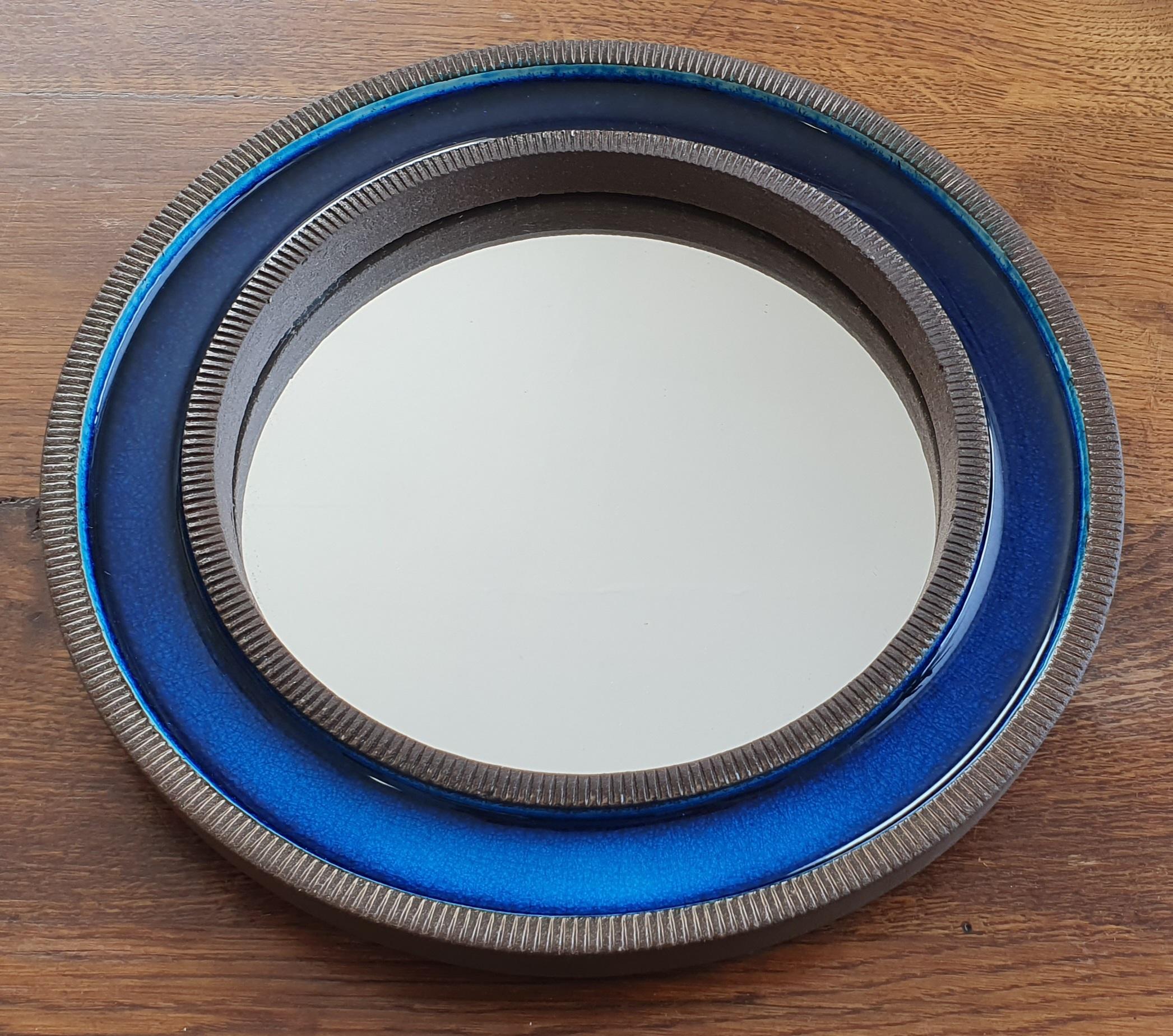 Blue midcentury round ceramic wall mirror designed by Erik Reiff for Danish Knabstrup. The mirror is made of glazed ceramic and has alternating rings with a ceramic ribbed edge and a smooth blue crystalline glaze on the inside. The back is covered