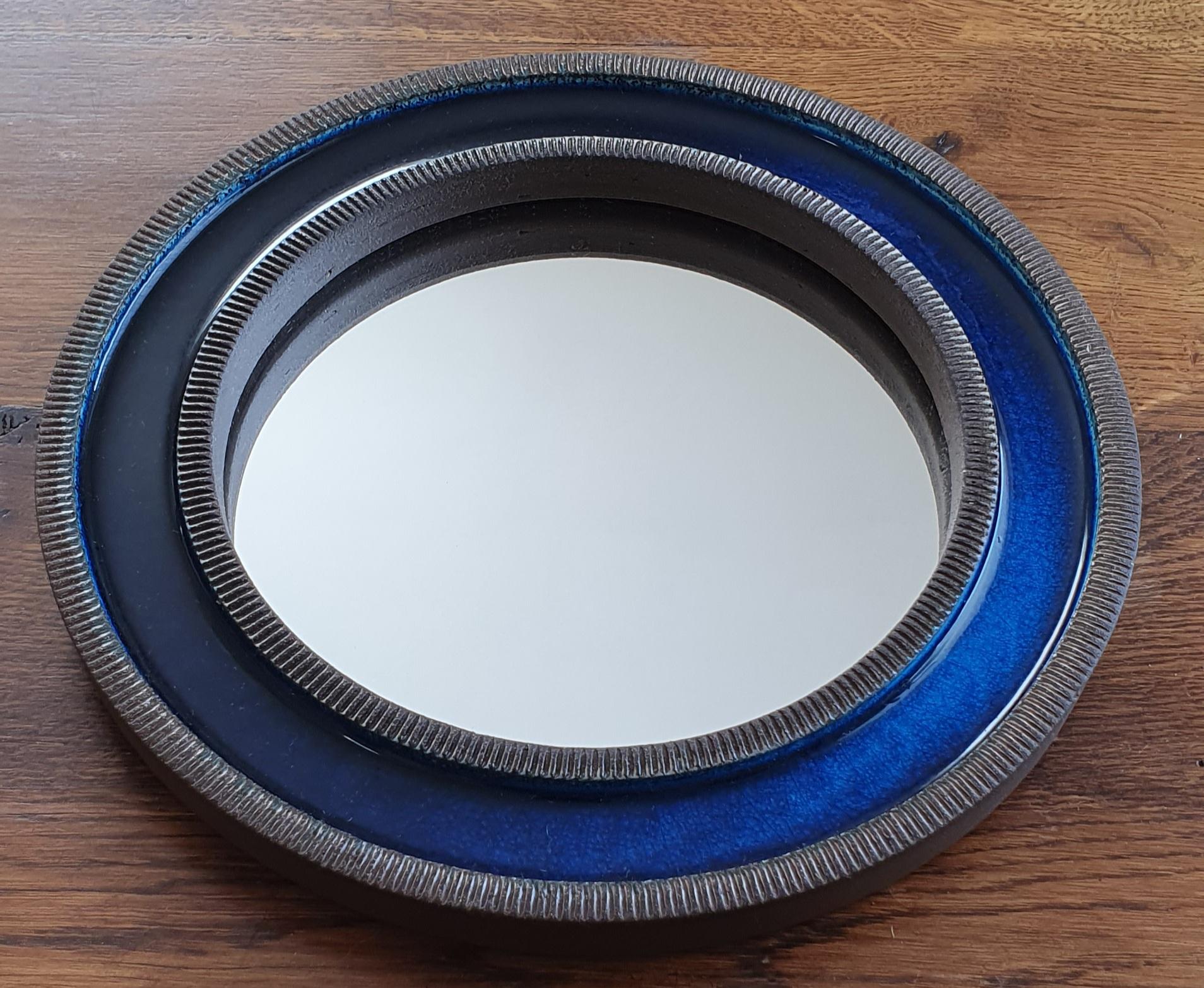 Blue midcentury round ceramic wall mirror designed by Erik Reiff for Danish Knabstrup. The mirror is made of glazed ceramic and has alternating rings with a ceramic ribbed edge and a smooth blue crystalline glaze on the inside. Original metal hook