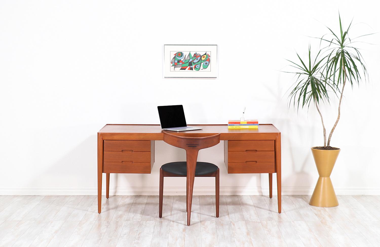 Danish Modern executive desk designed by Erik Riisager Hansen and manufactured by Haslev Møbelsnedkeri in Denmark, circa 1950s. This sleek design features a teak wood case with tall spindle legs and six front drawers creating an eye-catching profile