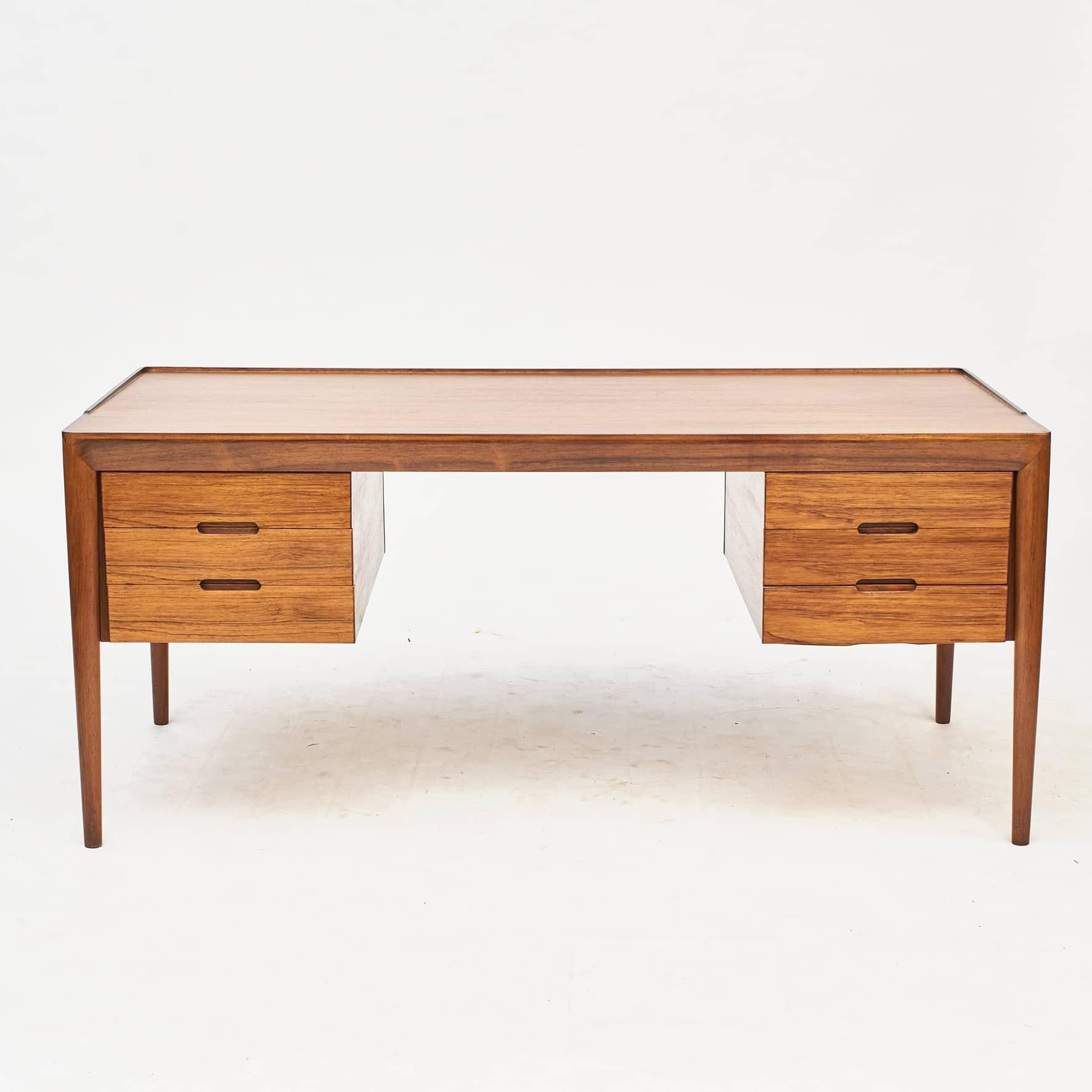 Freestanding Rosewood writing desk, model 66,
designed by Erik Riisager Hansen.
Tabletop with raised edge.
2x3 drawers with integrated pulls. Top drawers has sliding lids for use as extra workspace.
Round tapered legs.
Produced by Haslev