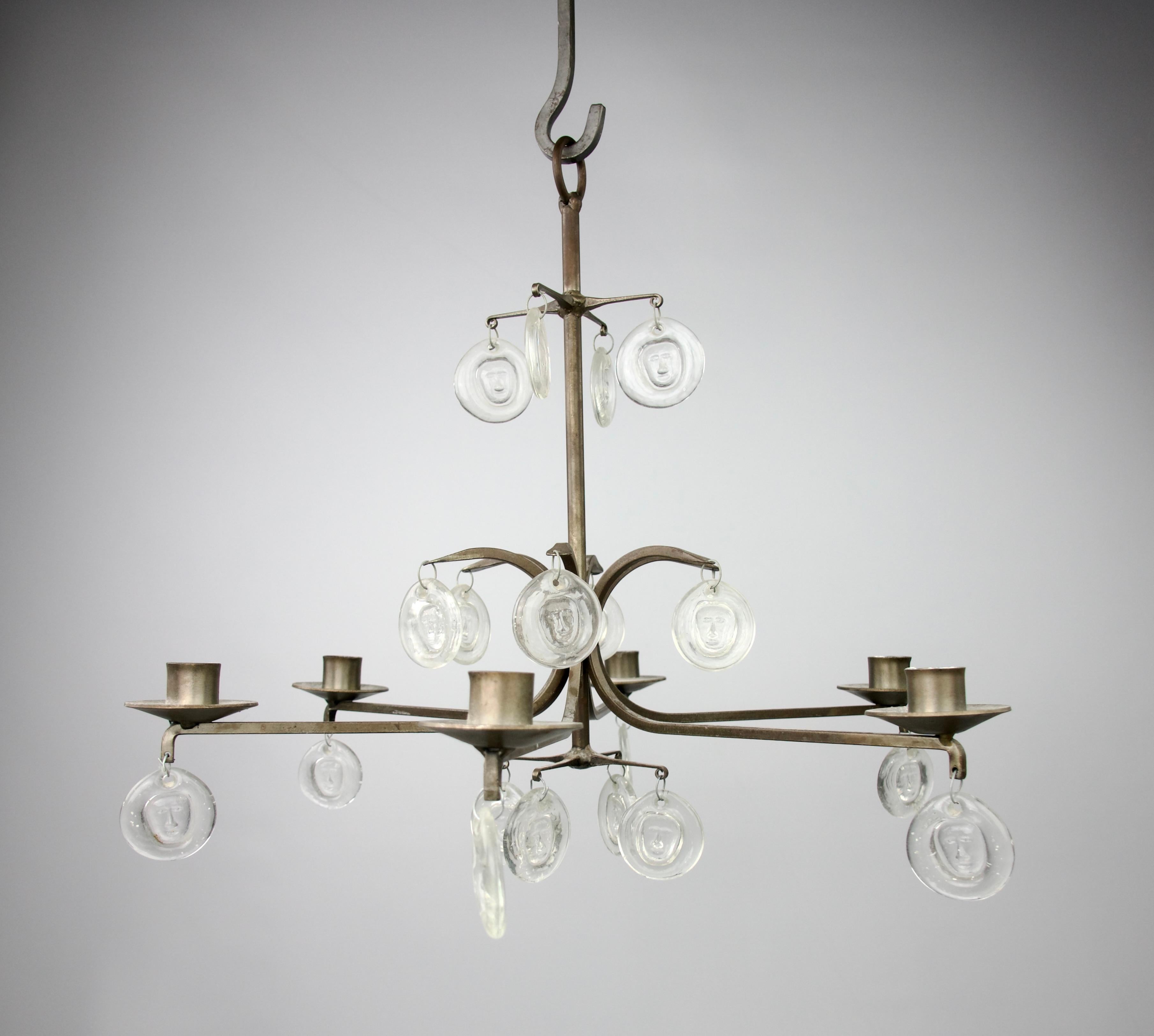 Superb six-armed chandelier by Erik Sylvester Höglund for Kosta Boda, Sweden 1965. Decorations of two sided pressed-glass face pendants.

In very good condition. Slight signs of use.

Dimensions in cm ( H x D ) : 43 x 50

Secure shipping.