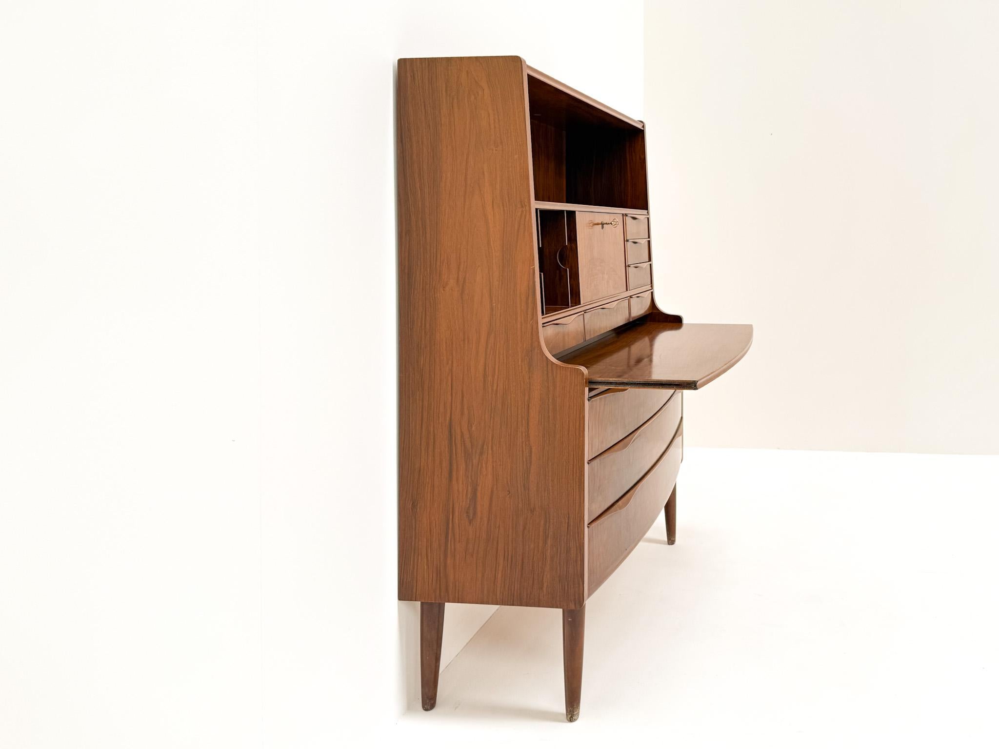 Este elegante escritorio de secretaria fue diseñado por Erling Torvits en Dinamarca en la década de 1960. Fabricada en hermosa chapa de nogal natural, presenta los característicos frentes de cajón esculpidos en 