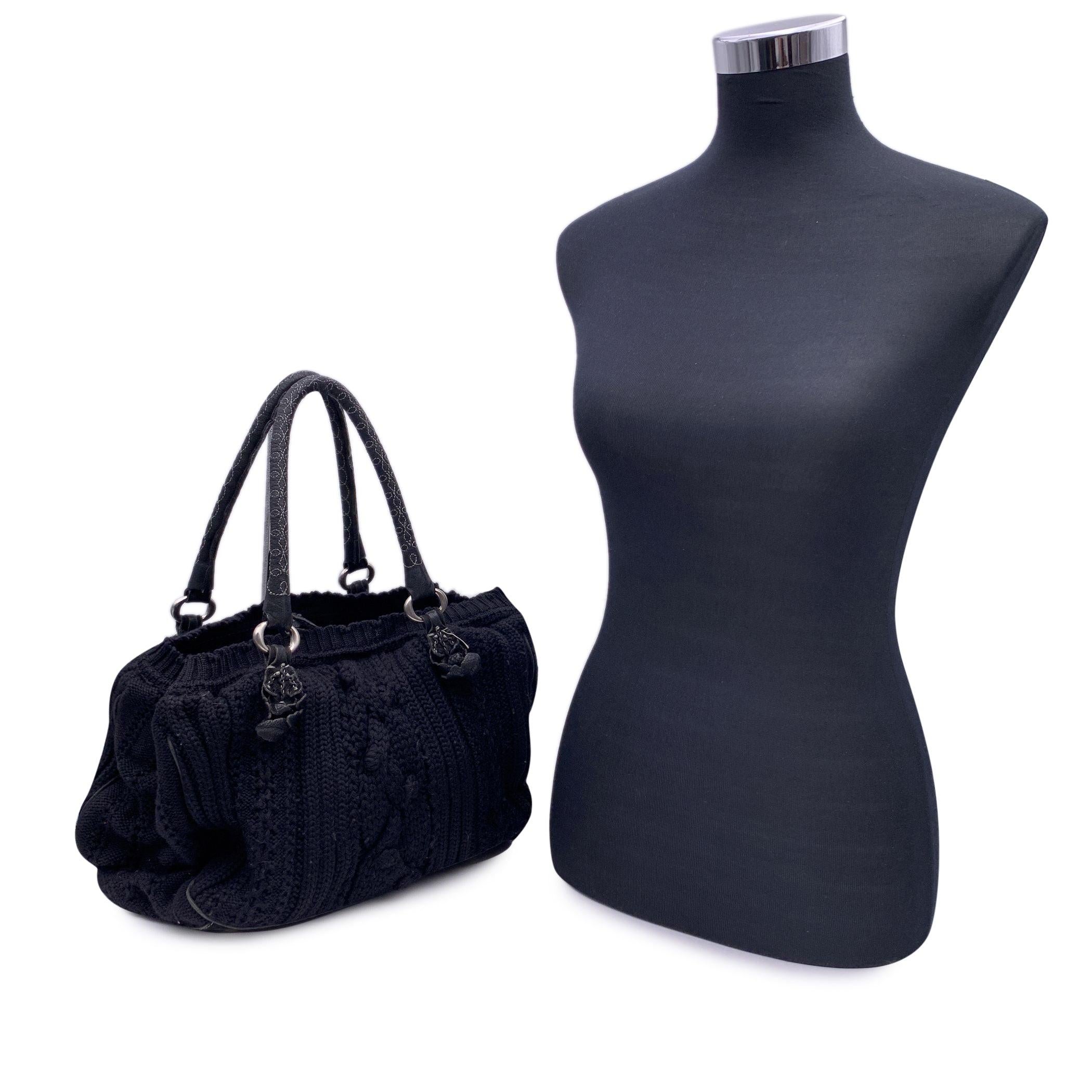 Ermanno Scervino black wool knit tote bag. Leather trim and handles. Contrast stitching. Self-tie closure on top. Black suede lining. 2 main compatments and 1 middle zip section . 1 side zip pocket and 2 side open pockets inside. 'Ermanno Scervino'