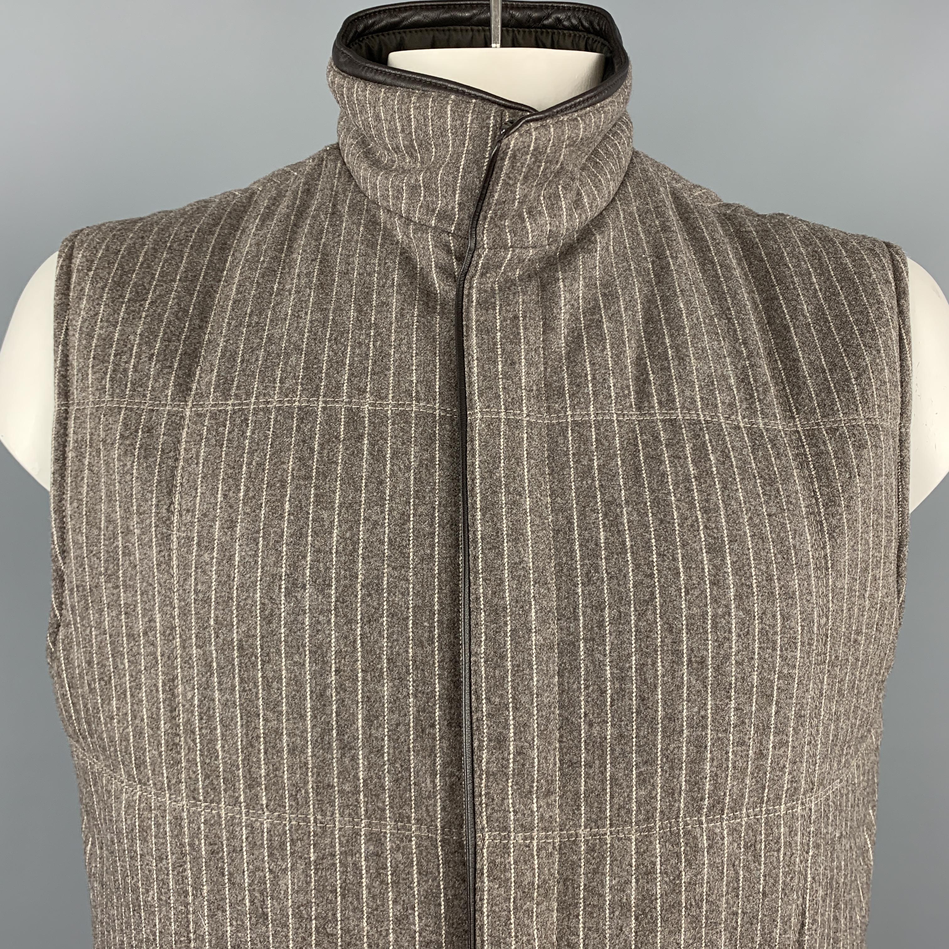 This classic ERMENEGILDO ZEGNA vest comes in a muted taupe gray & cream pinstriped wool cashmere blend felt and features a high collar, hidden double zip closure, chocolate brown leather piping, and four zip pockets. Reversible to a deep brown nylon
