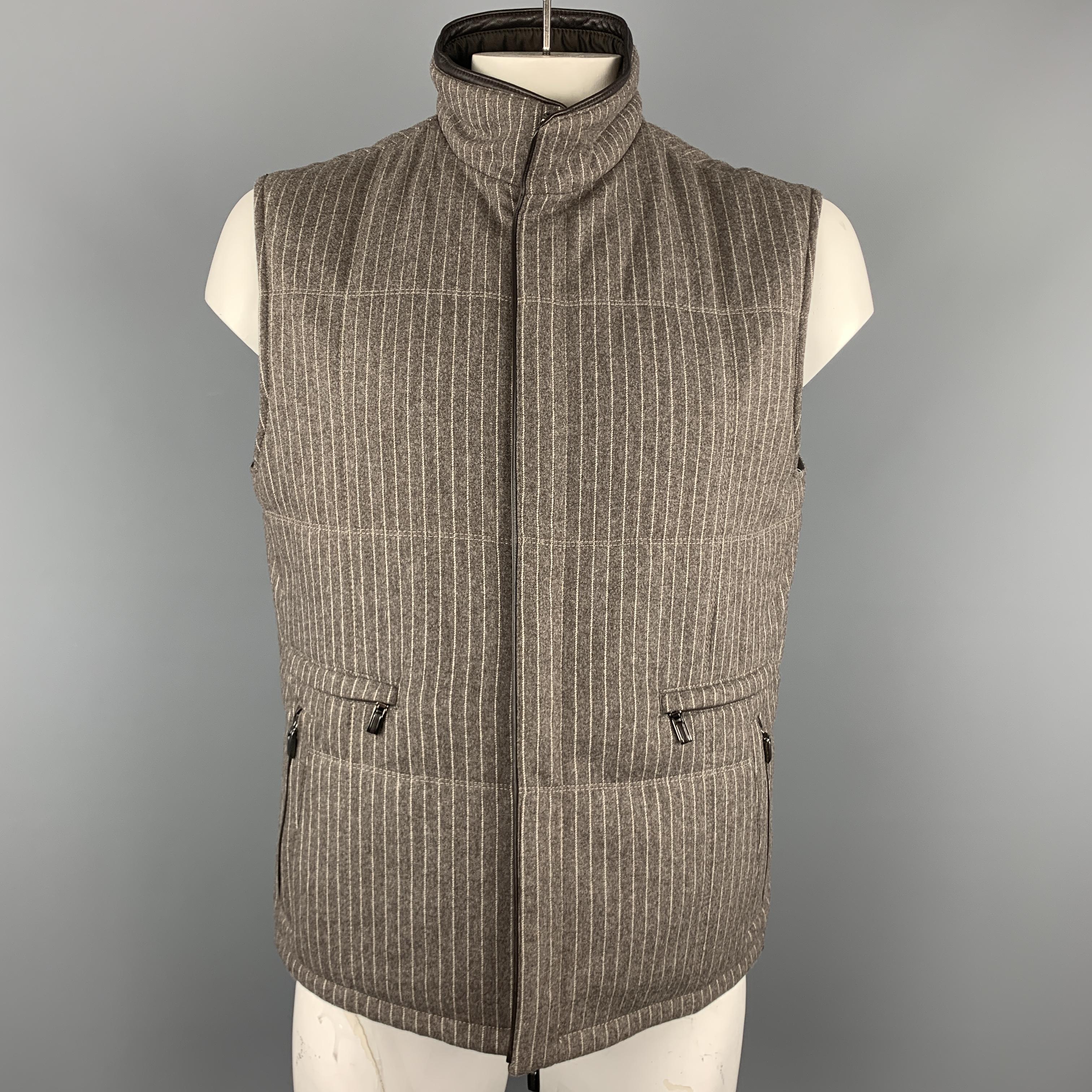 This classic ERMENEGILDO ZEGNA vest comes in a muted taupe gray & cream pinstriped wool cashmere blend felt and features a high collar, hidden double zip closure, chocolate brown leather piping, and four zip pockets. Reversible to a deep brown nylon