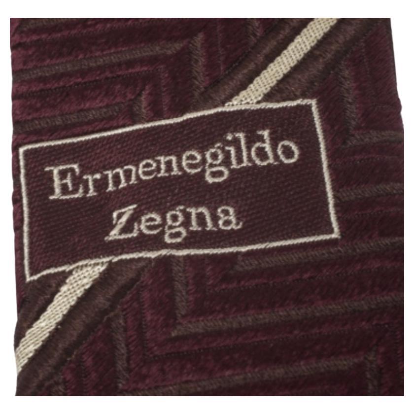 Cut from quality silk, this burgundy Ermenegildo Zegna Vintage tie features a chevron pattern in jacquard all over. The piece is complete with a keeper loop on the back. Look smart by pairing it with plain shirts.