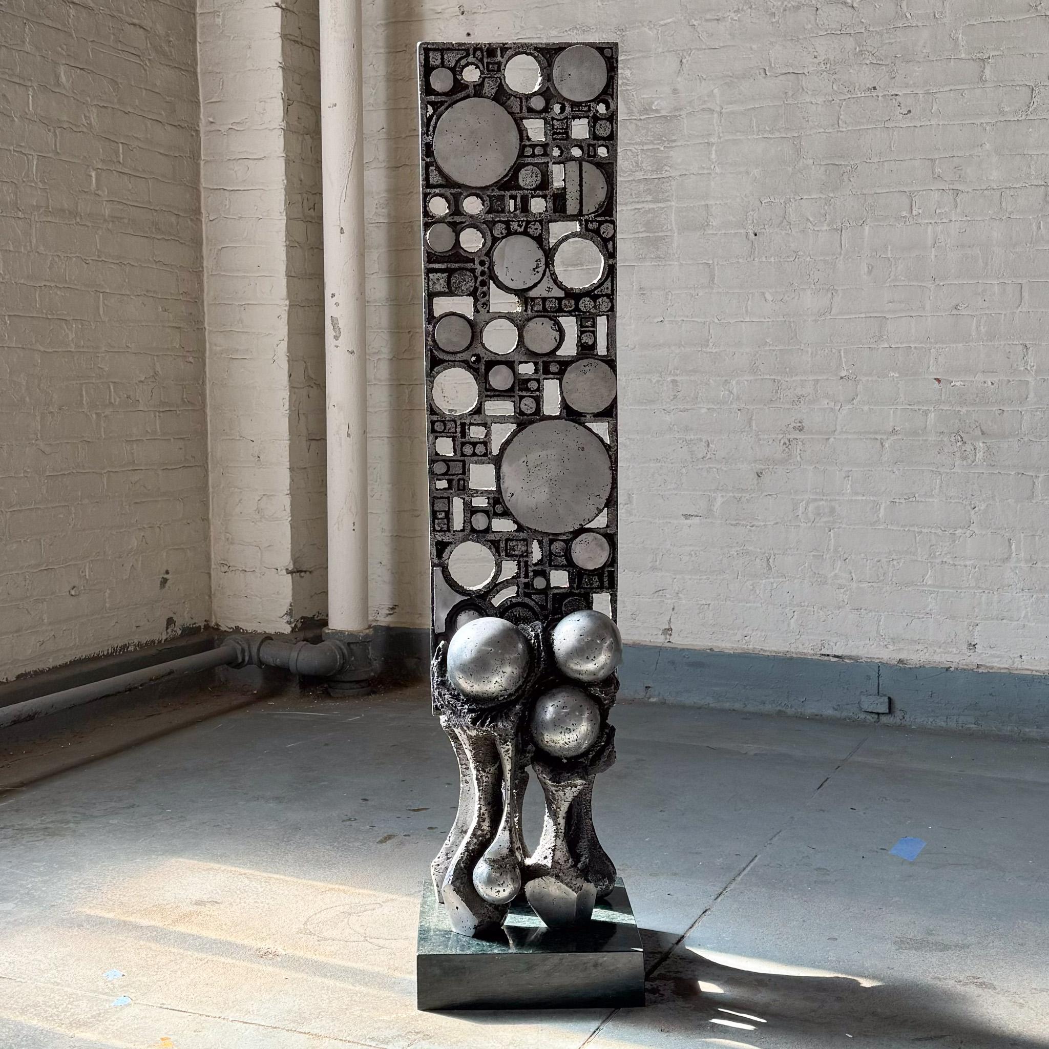 Floor-standing sculpture of cast and hand-cut aluminum, sitting atop a polished green marble base. A 1970 creation by British sculptor Ernest Bottomley (b. 1934). Bottomley, a student of Graham Sutherland and Norman Webster, received a National