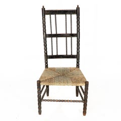 Ernest Gimson. Una rara silla baja con asiento de junco torneado de bolillos ebonizados de la escuela de Cotswold