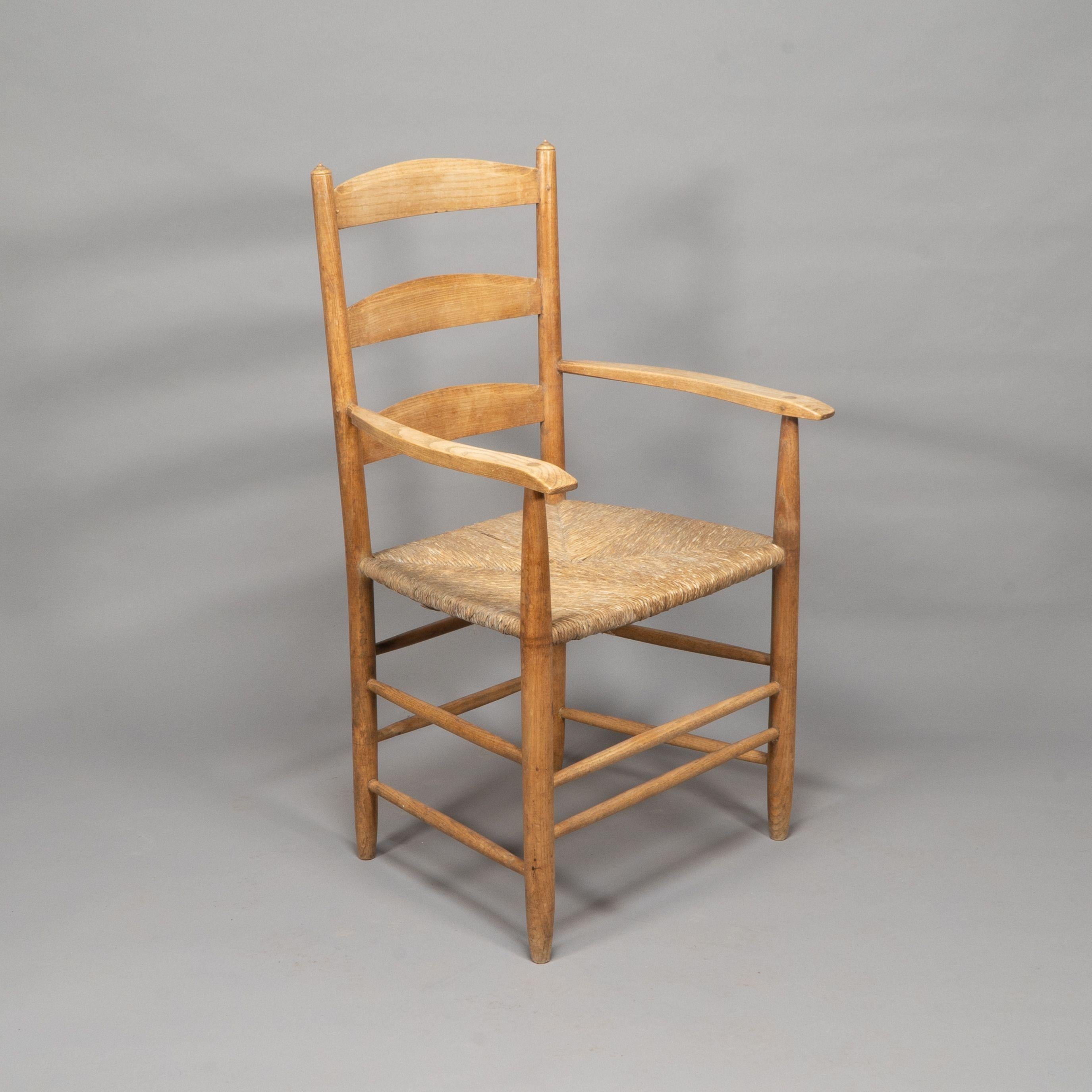 Ernest Gimson made by Edward Gardiner. An Arts and Crafts ash ladder back Bedales armchair. With three ladders each chamfered to top of each ladder, the top ladder is pegged with through joints to the arm supports, and full circle scribe marks to