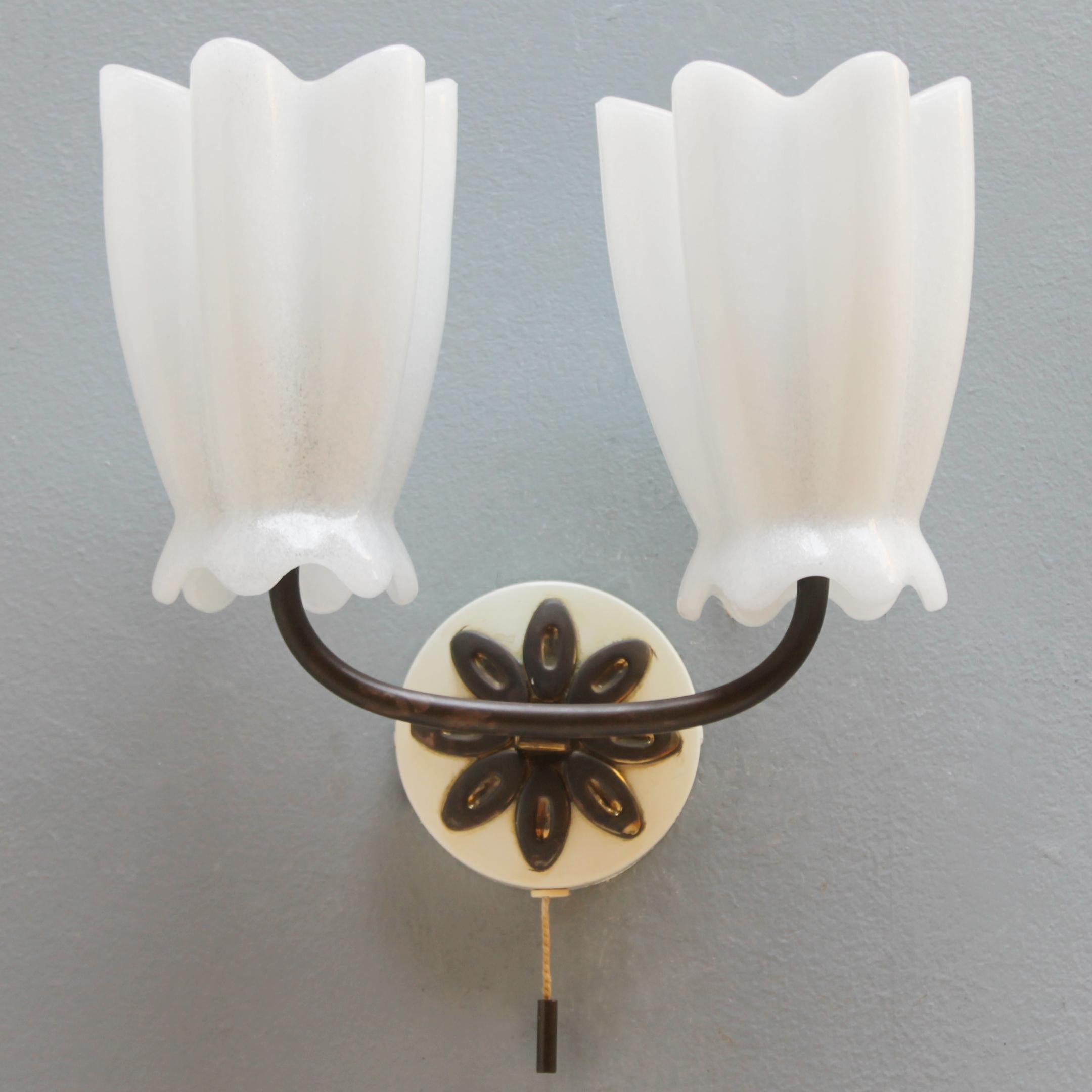 Elegant wall lamp from the company Hillebrand, Germany. Metal, brass and white pate-de-verre (molten glass). This model with a pull function is from the 1950s and is not often seen. Marked with a label. 
Little remains of the gilding, but still a