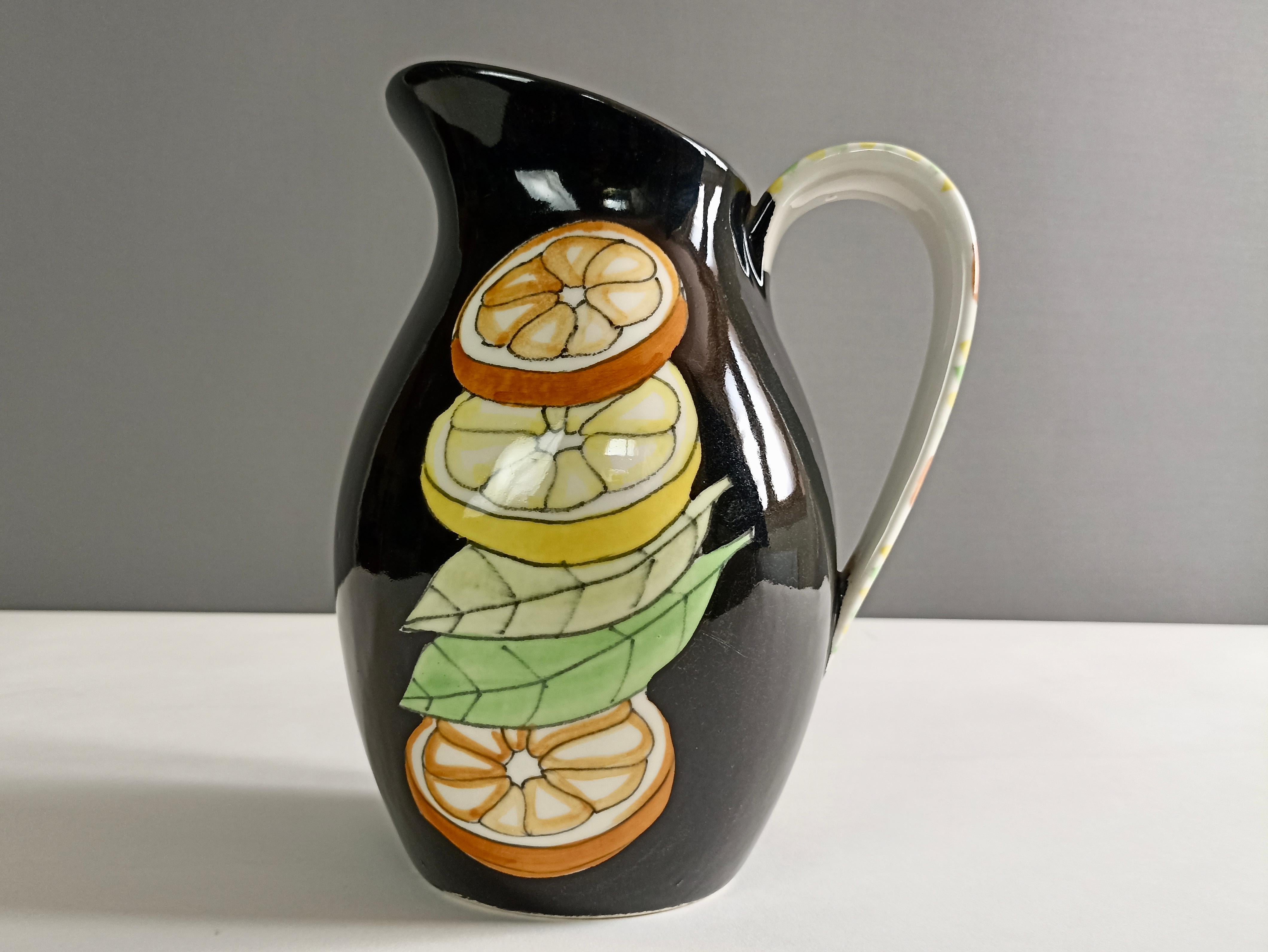 Elegant majolica jug from the 1950s, hand-painted with a citrus subject on both sides, attributable to the production of Ernestine Ceramics Salerno, Italy.
This famous brand takes its name from the American decorator Ernestine Virden Cannon