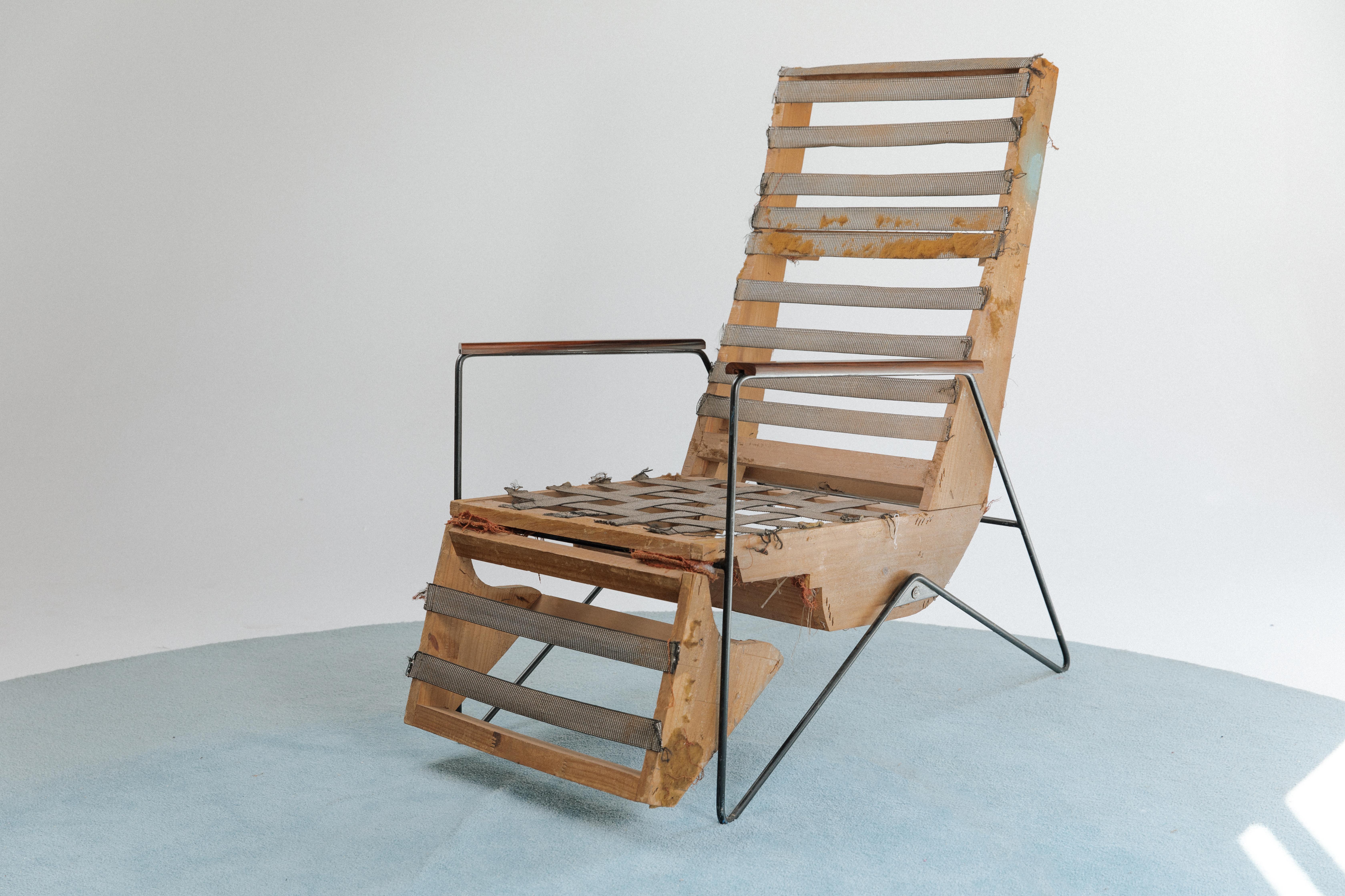 Reclining lounge chair by Ernesto Hauner for Ernesto Hauner & cia. The chair stands on thin metal legs and has wooden armrests. The upholstery has been removed, exposing the pinus frame and the wonderful and original rubber tire straps. When