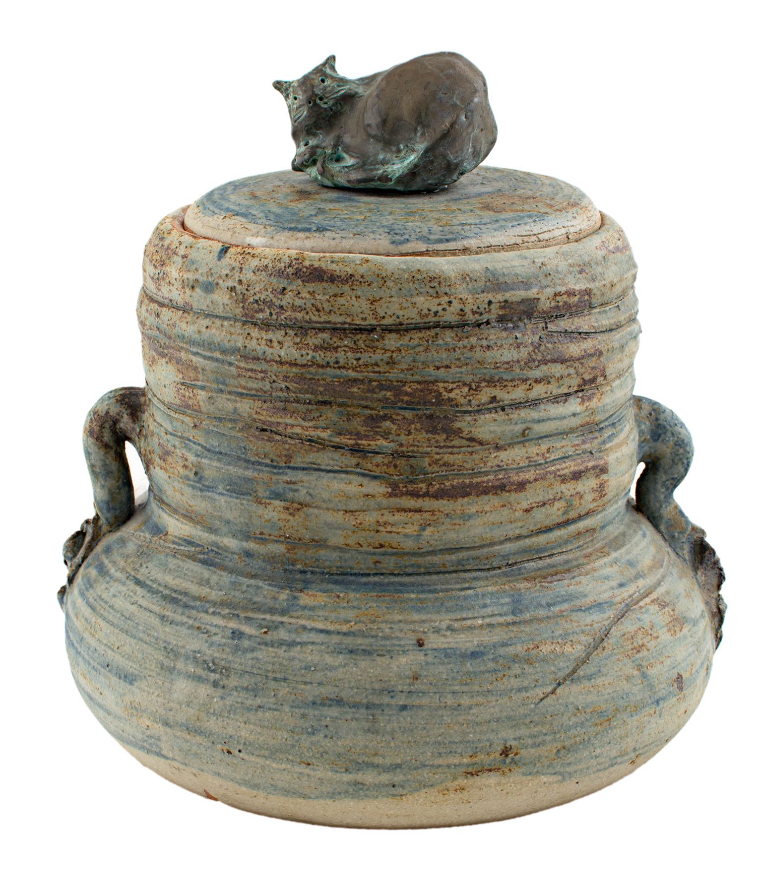 "Cover Jar w/ Cat" is a stoneware and bronze sculpture by Ernst Gramatzki. It features horizontal lines around the piece and a bronze cat on top of the vessel. 

7 1/2" x 7"

Ernst Gramatzki is a world renowned artist, sculptor, potter, painter and